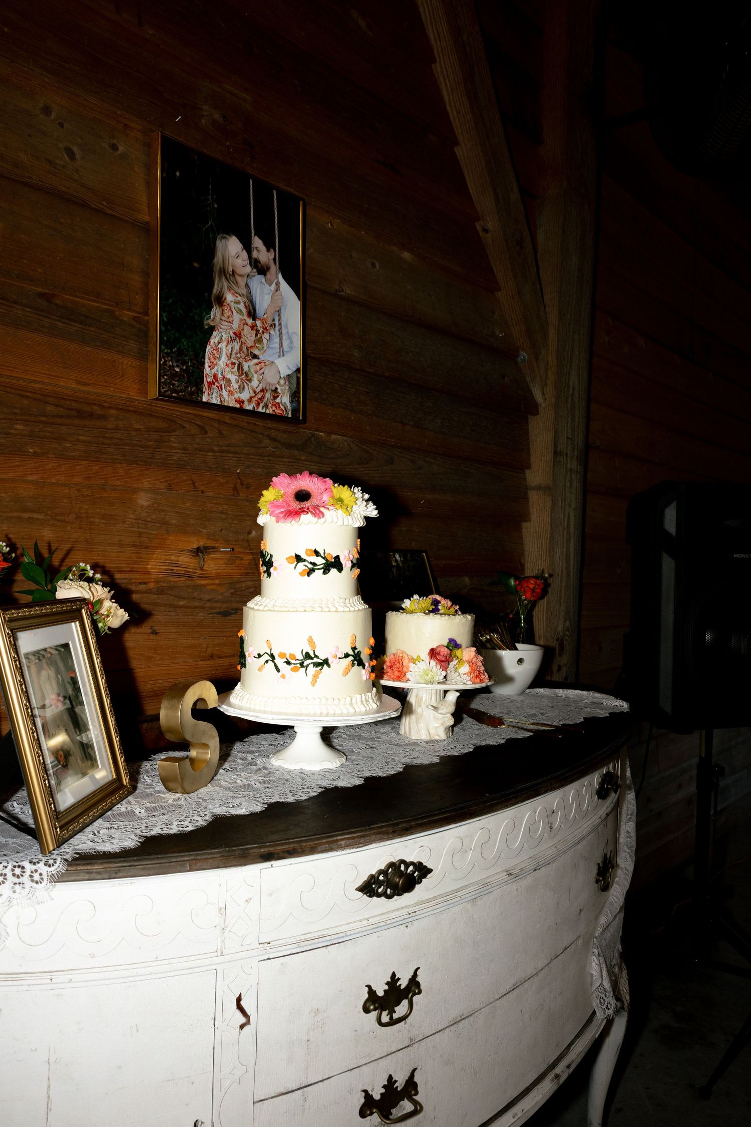 Emotional bride hugging guest during wedding reception dance at warmly lit rustic barn venue.