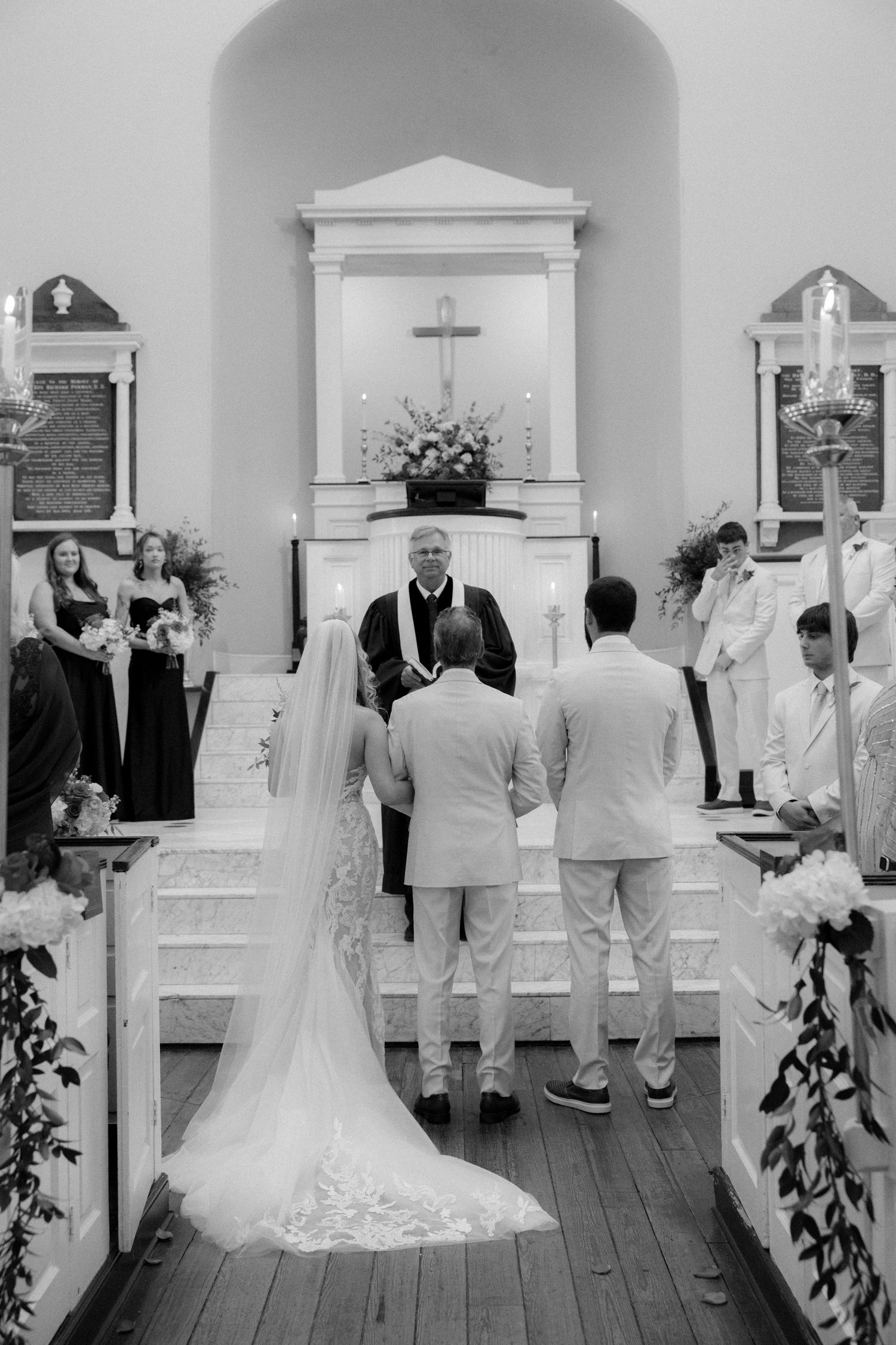 Bride and groom stand before the altar with officiant during a traditional church wedding ceremony.