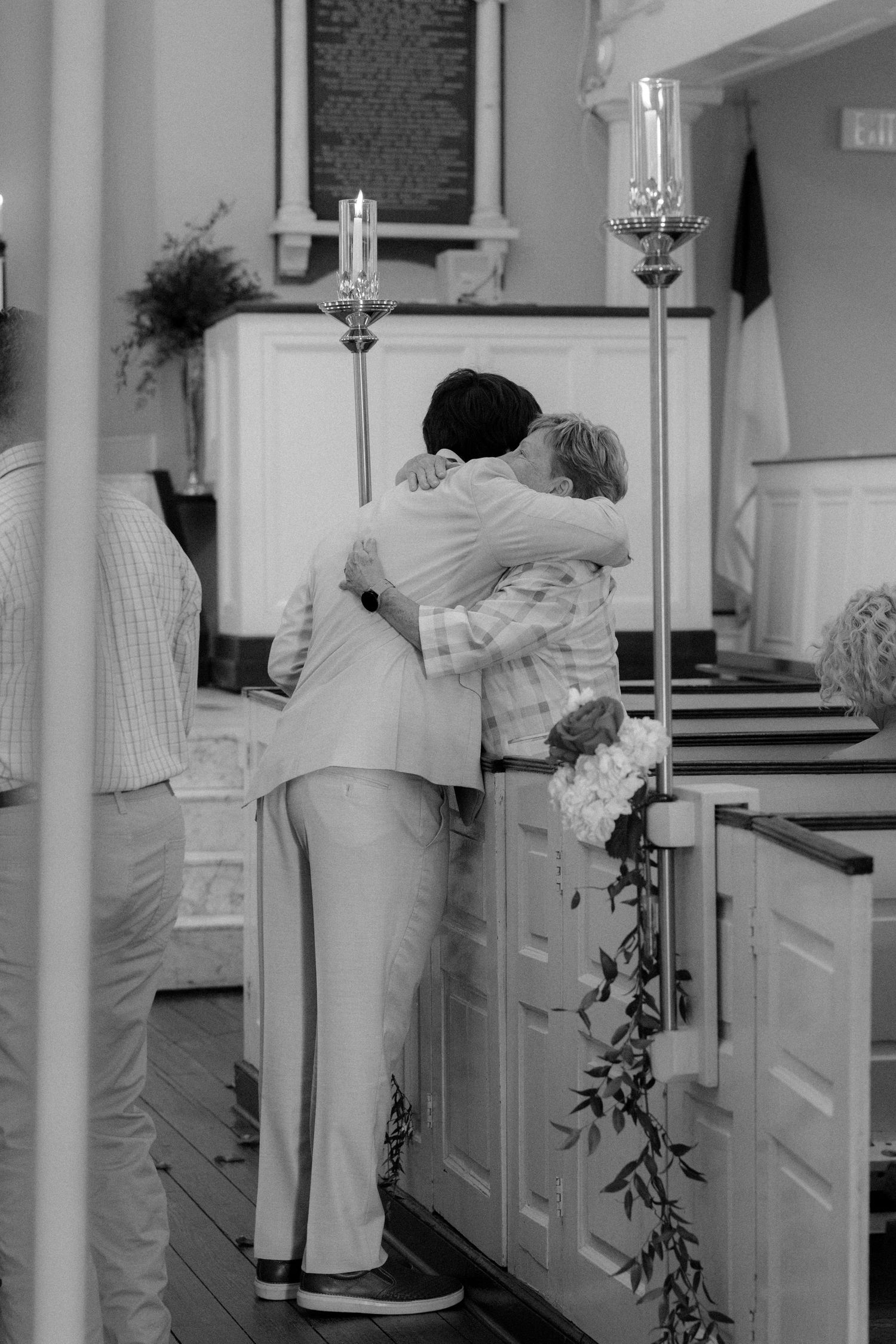Two people share an emotional hug at the altar of a church during a wedding ceremony.