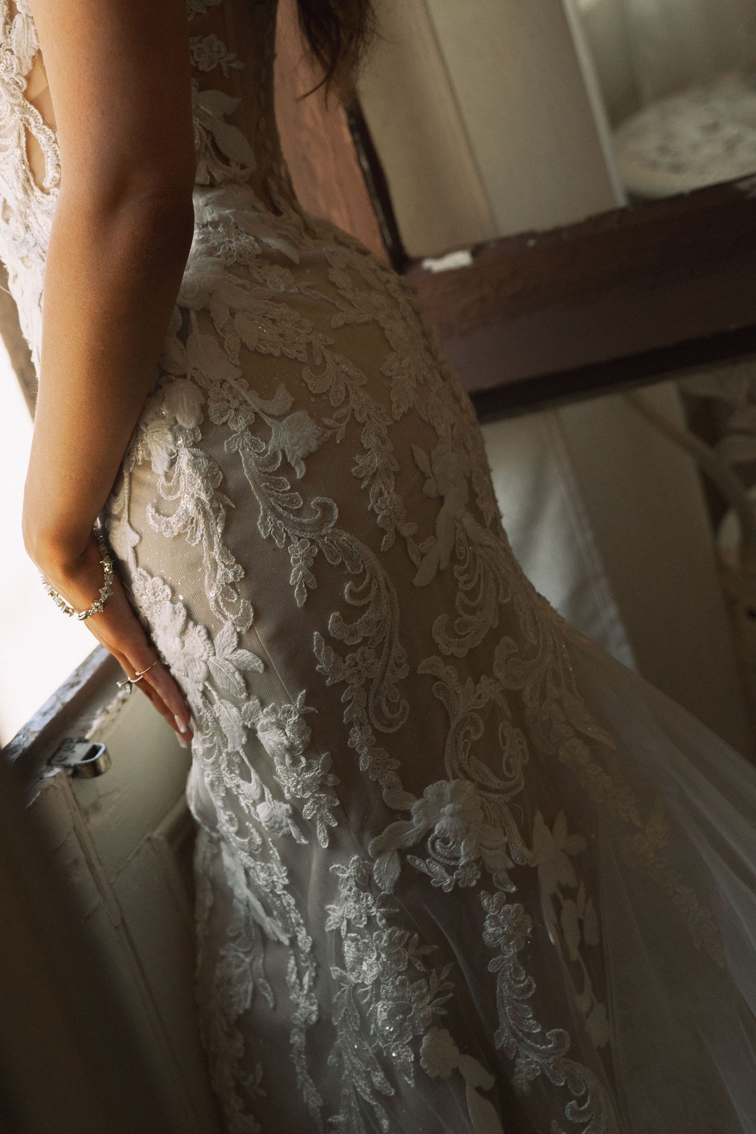 Close-up detail of intricate lace embroidery on back of elegant fitted bridal wedding gown.