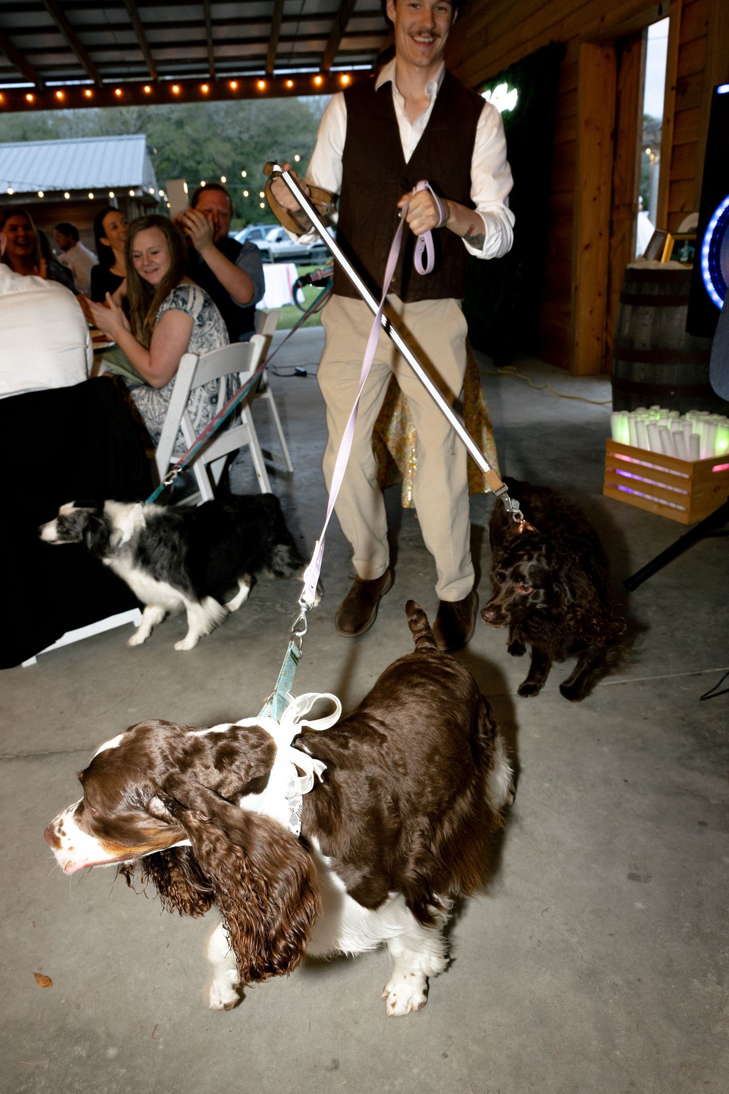 Bride in lace gown and groom in tan suit celebrating grand entrance at rustic barn wedding.