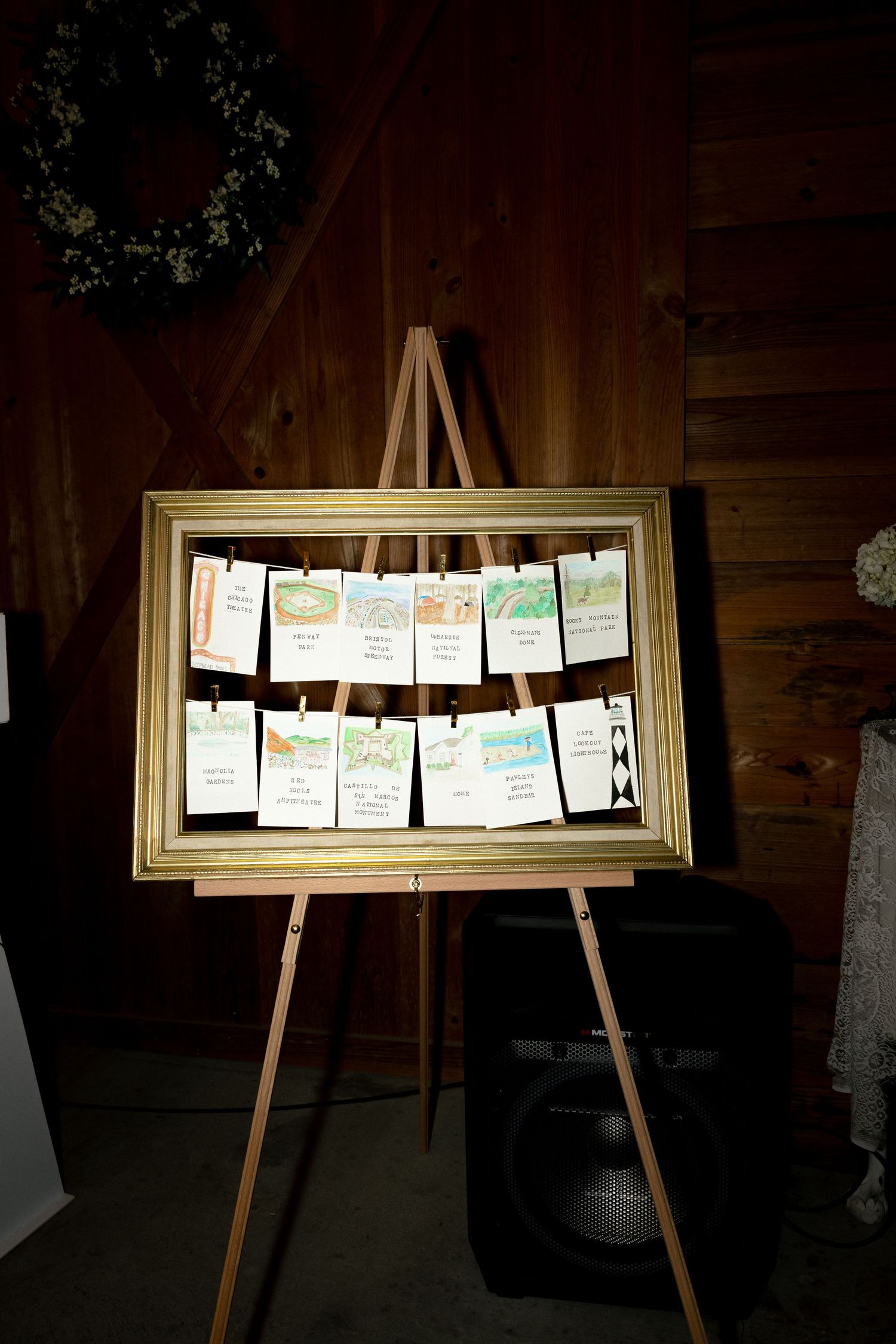 Two-tier white floral wedding cake on vintage dresser with couple photo in rustic barn venue.