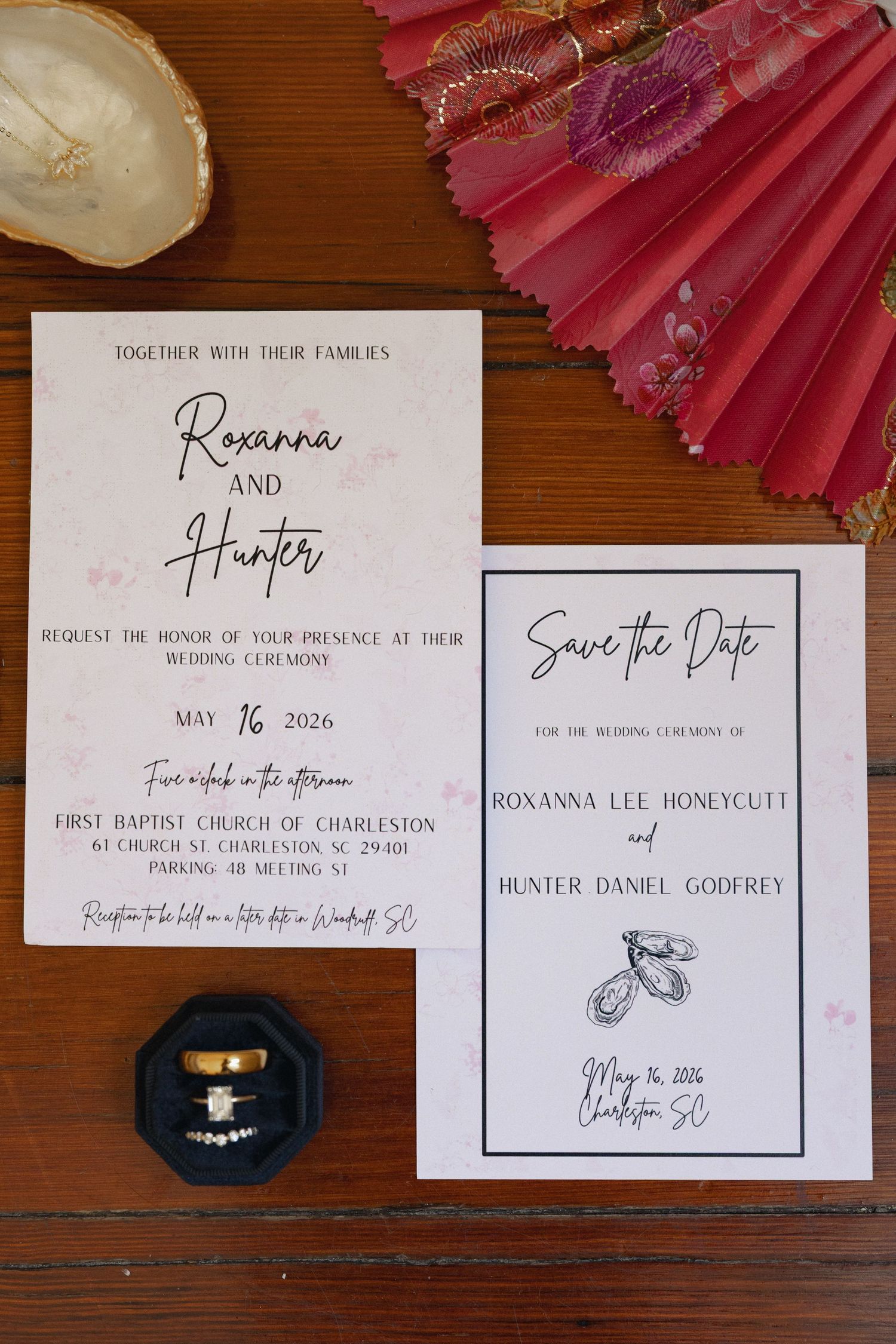 Wedding invitation suite for Roxanna and Hunter with save the date card and gold rings on wood table.