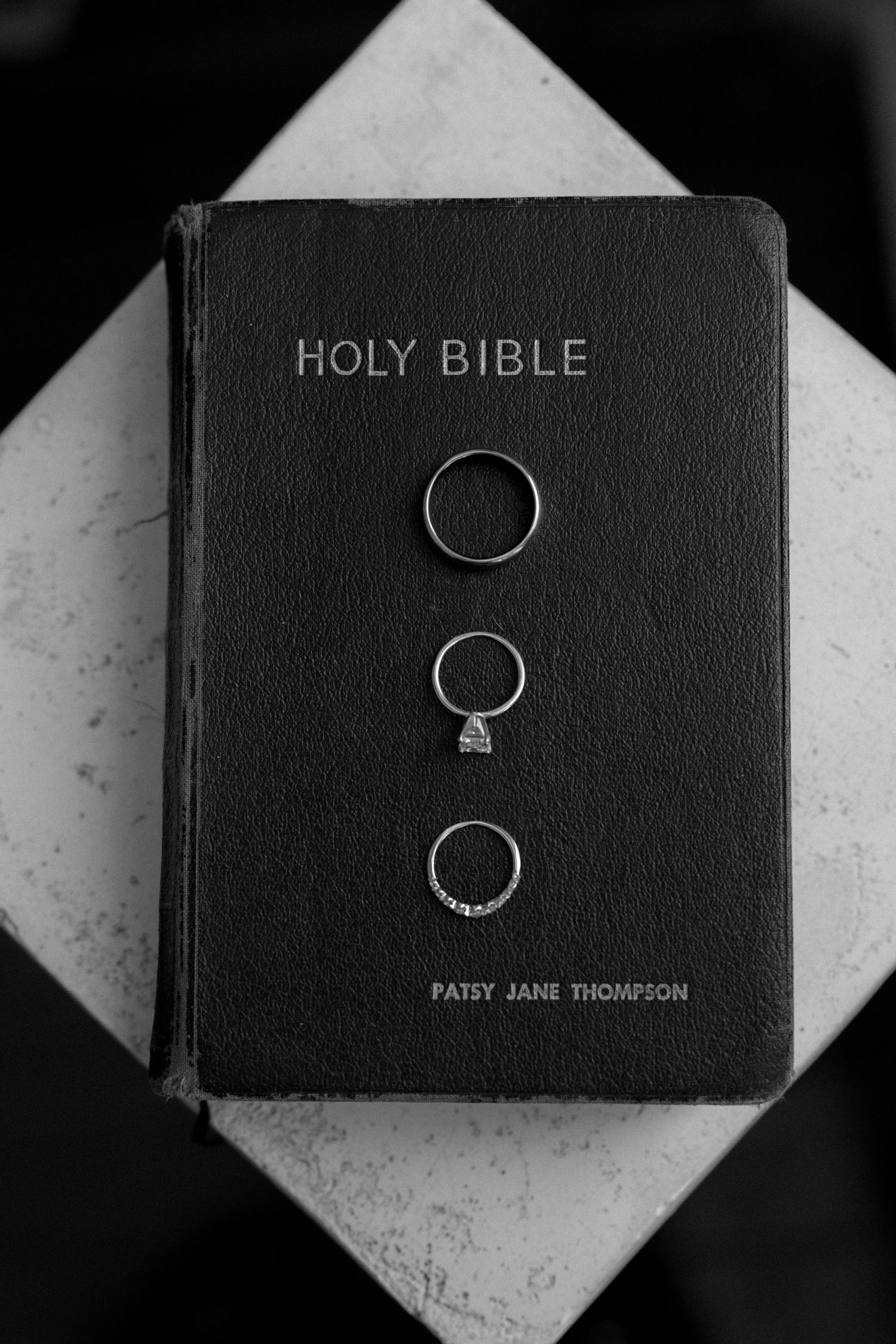 Three wedding rings displayed on a Holy Bible belonging to Patsy Jane Thompson, black and white photo.
