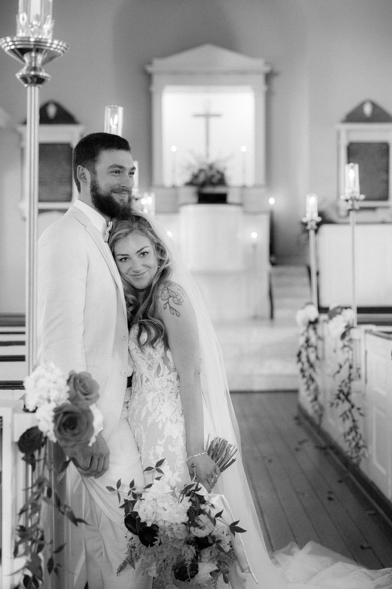 Black and white portrait of bride and groom posing together in a charming historic church interior.