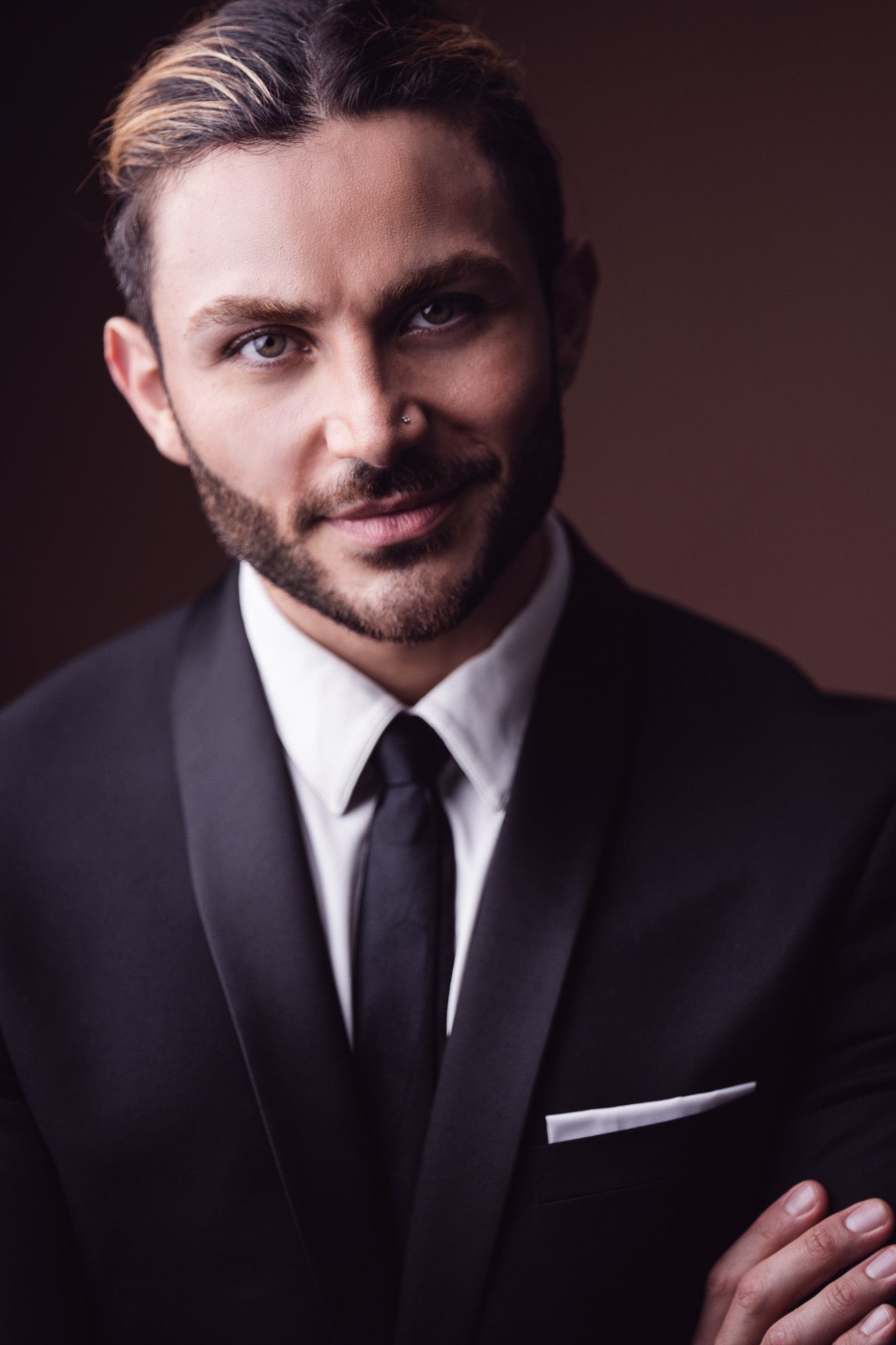 Professional portrait series showing different angles and expressions of someone in a black suit and tie against dark background.
