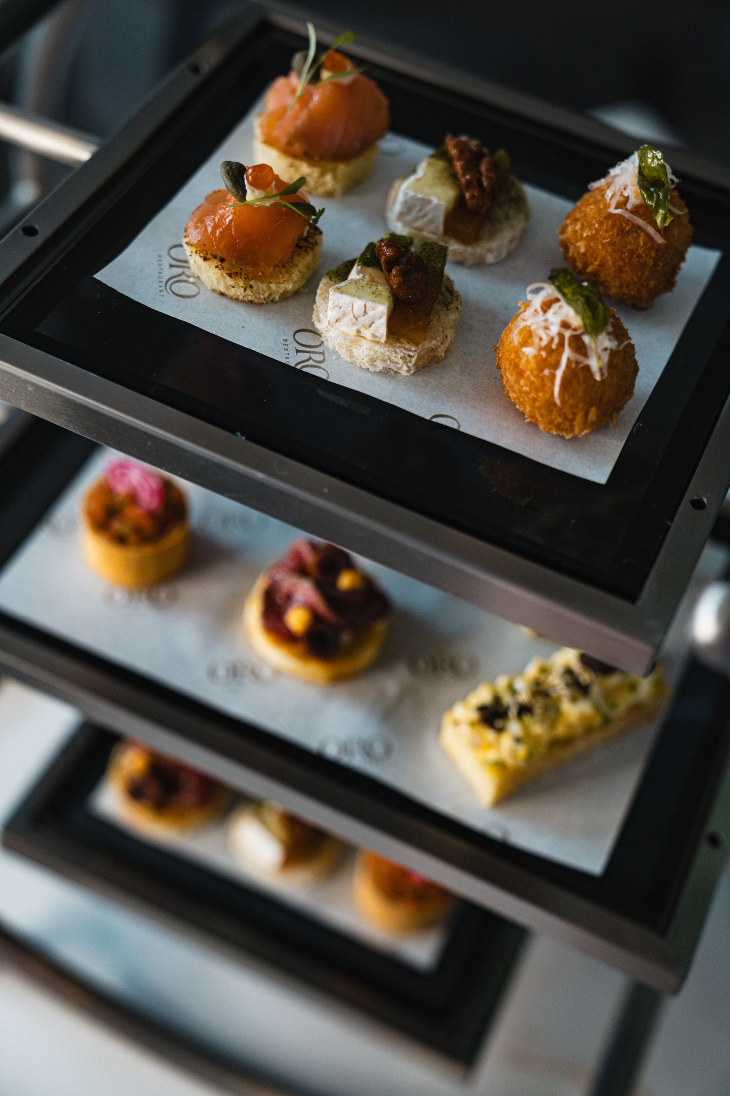 Artfully plated gourmet appetizers and canapes arranged on modern black serving platters.