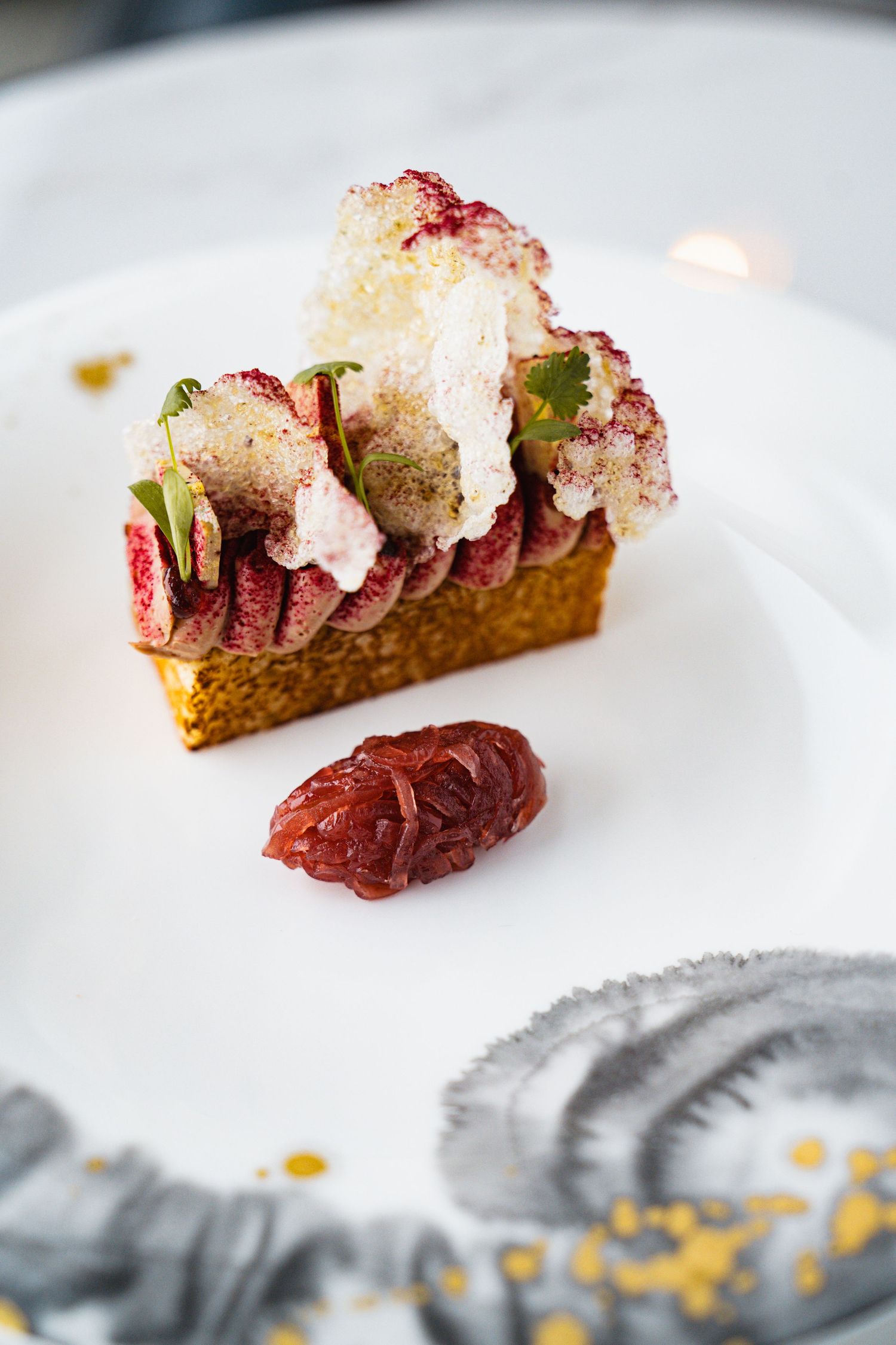 Elegant seafood appetizer with red garnish served on a white plate with artistic plating.
