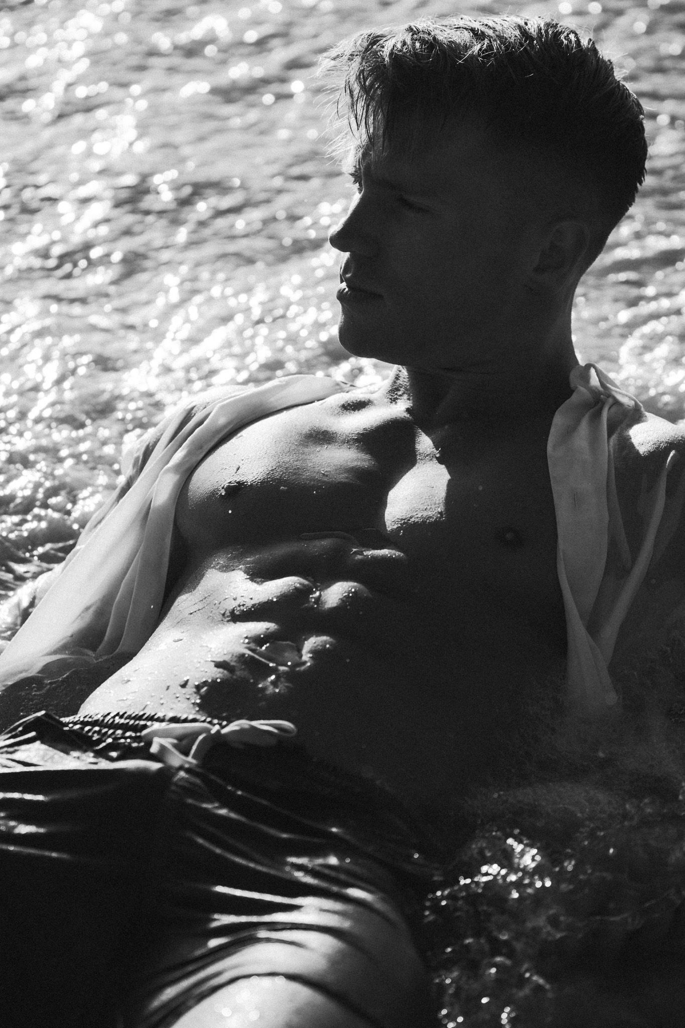 Black and white artistic sequence of a person floating in rippling water with dramatic lighting and shadows.