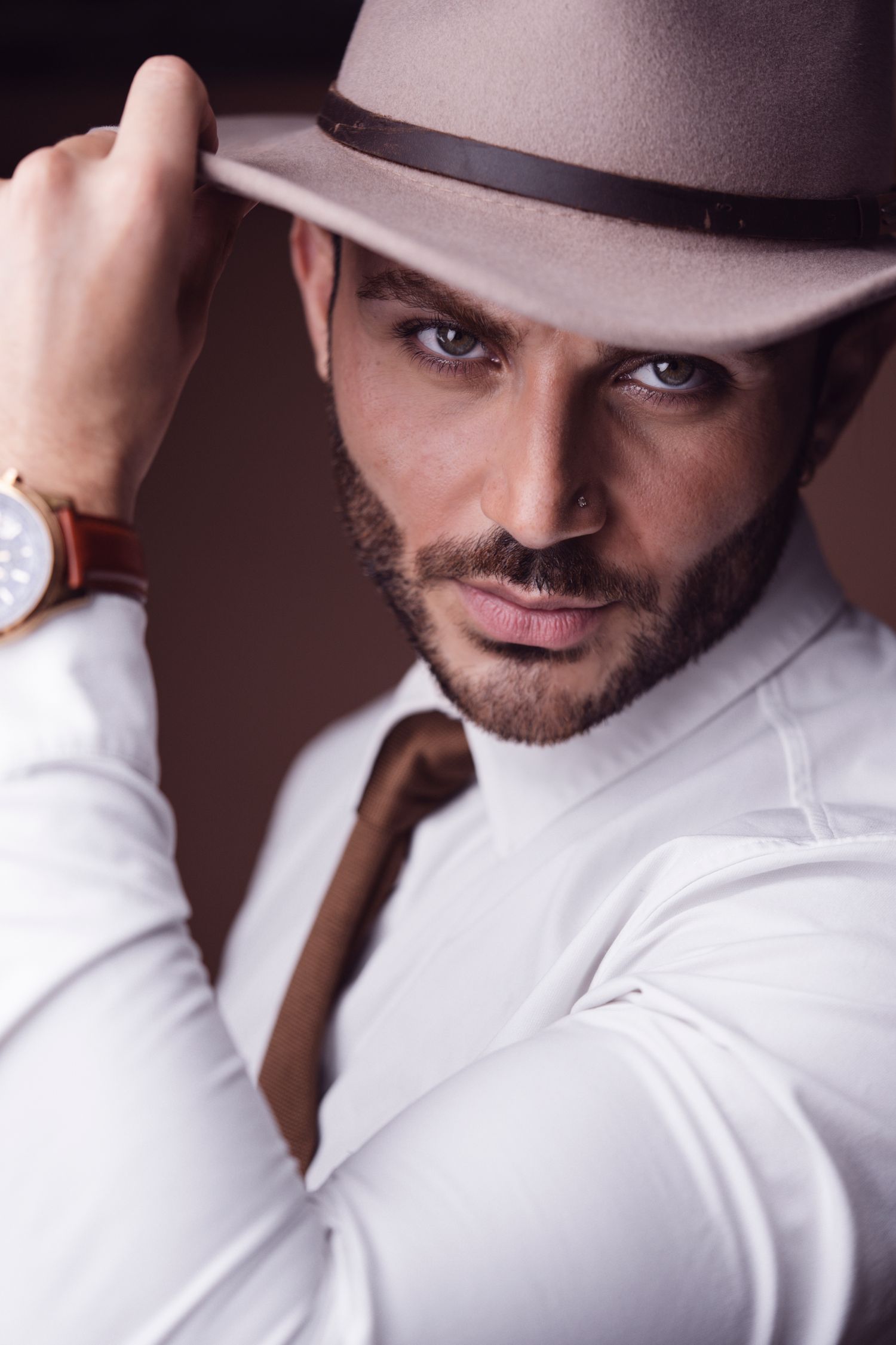 Portrait series showing a person in a white shirt and brown hat against a dark background.