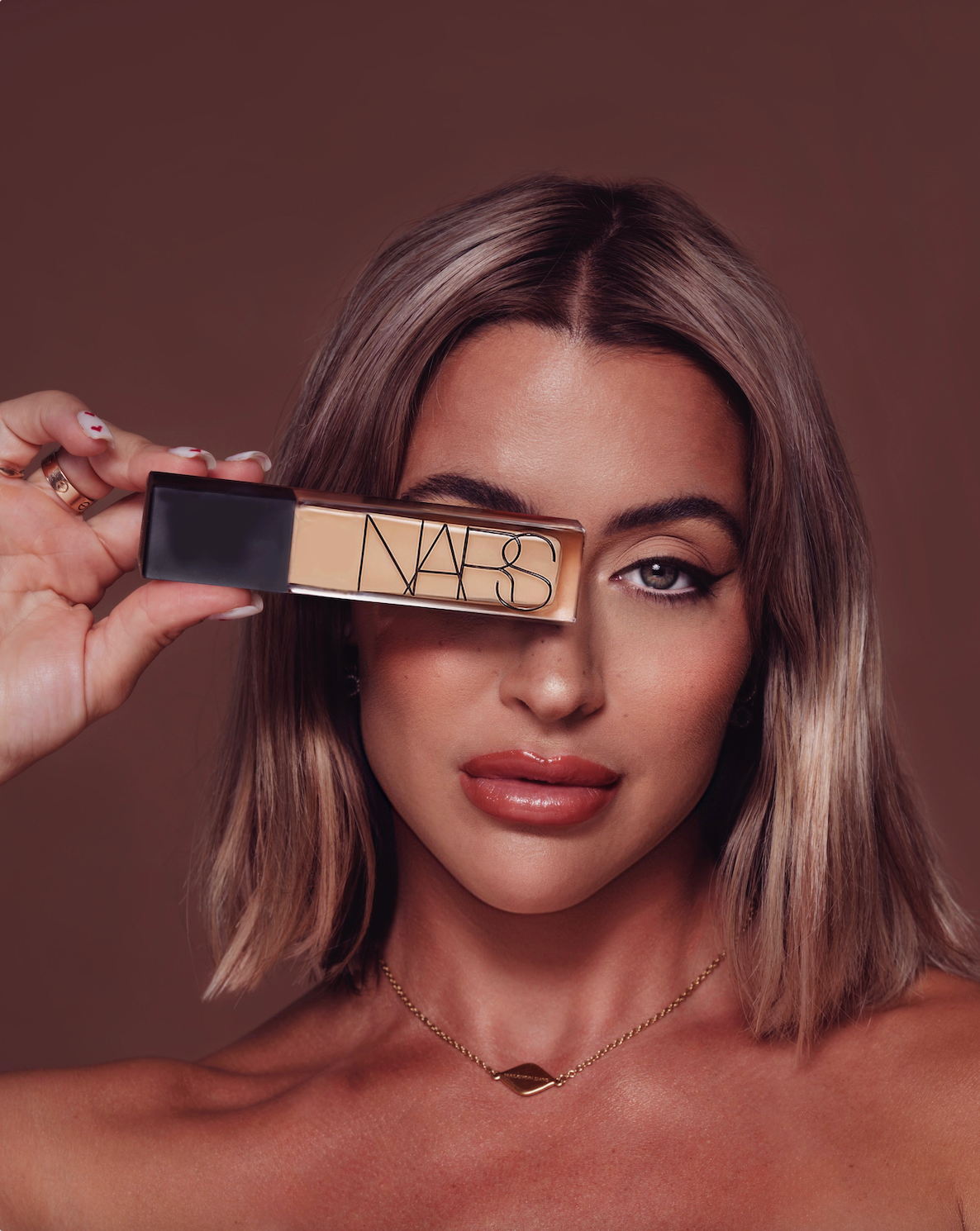 Close-up beauty shots showing glossy lips and NARS makeup product against warm brown background.