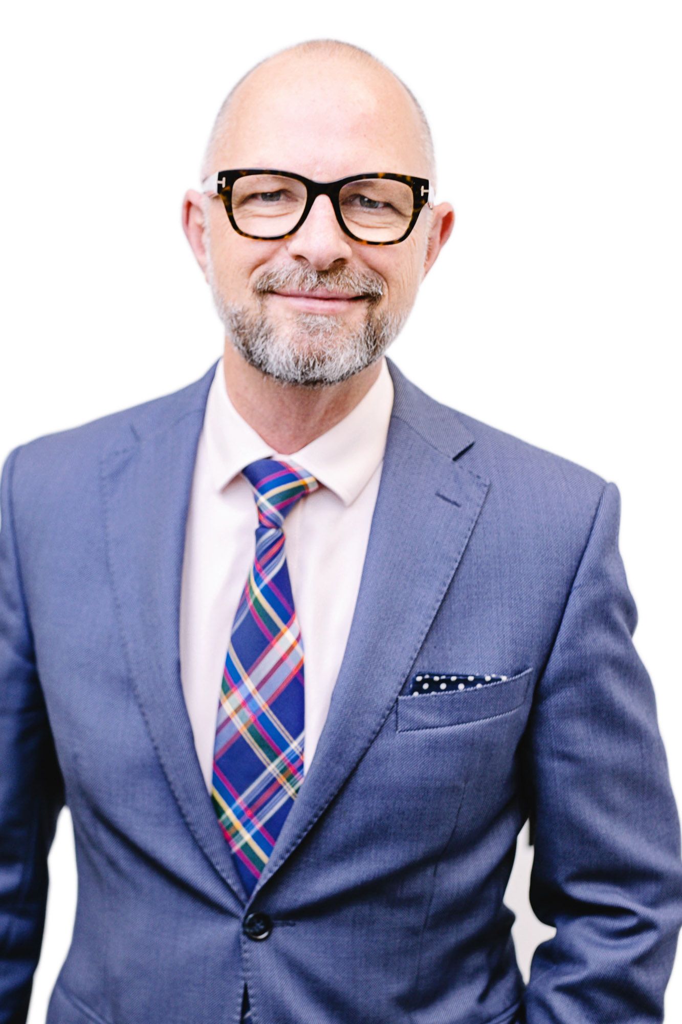 Professional headshot of a person in a blue suit wearing glasses and a colorful plaid tie.