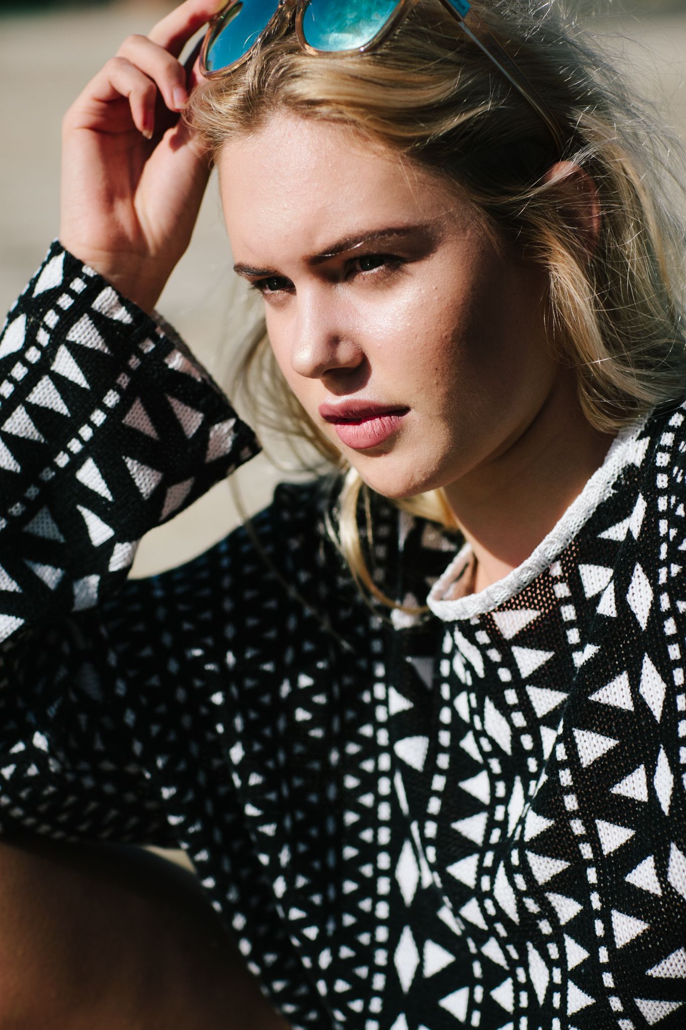 Close-up fashion portrait showing black and white geometric pattern sweater details.