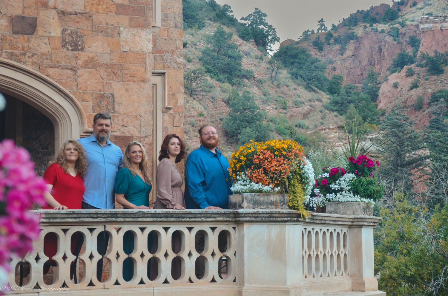 Outdoor family portrait on a stone balcony surrounded by colorful flowers, beautiful architecture, and Colorado mountain scenery.