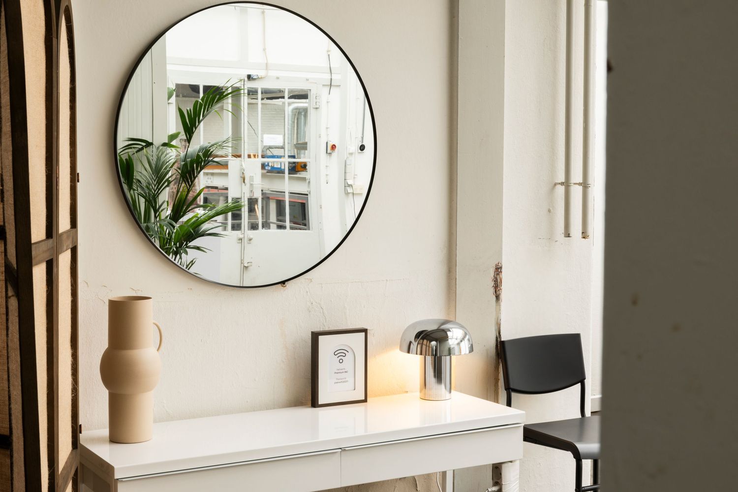 Modern entryway with circular mirror, console table, and minimalist decor against white walls.