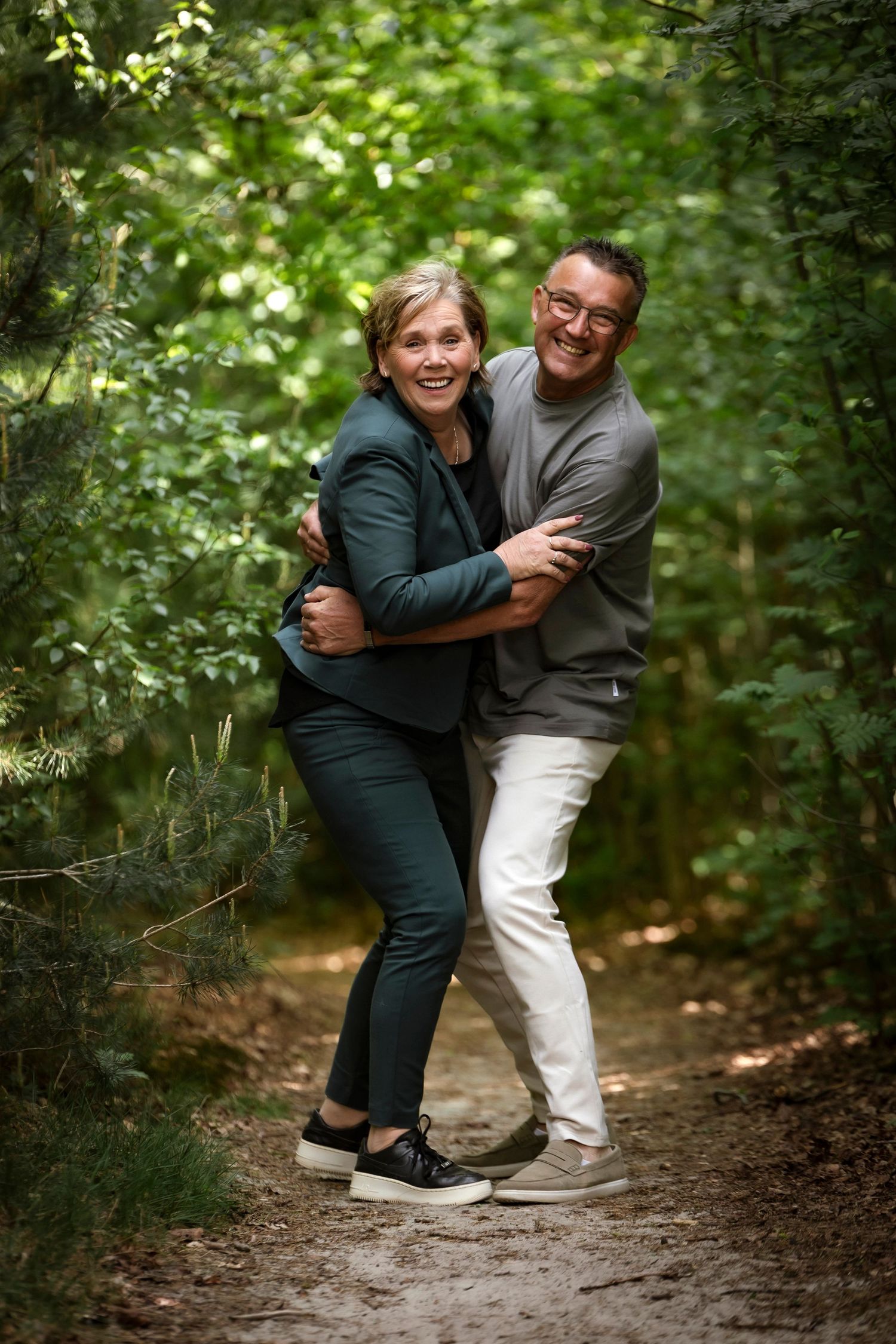 A couple sharing joyful moments together on a wooded nature trail.