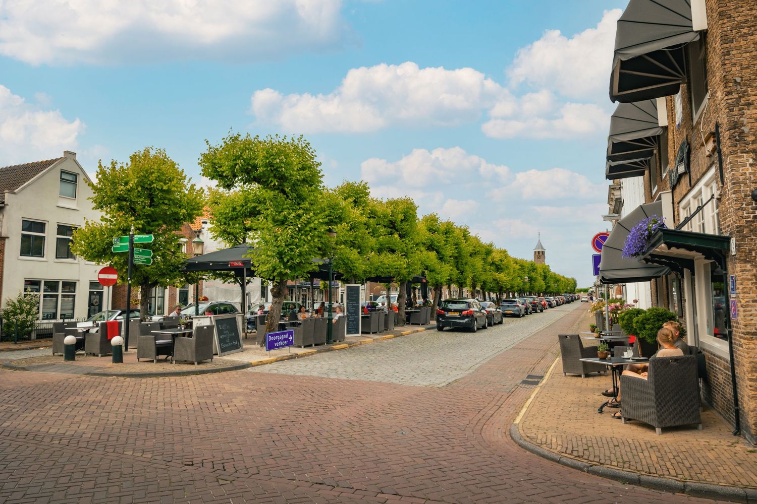 Charming brick-paved street lined with trees and local businesses in a quaint downtown shopping district on a sunny day.