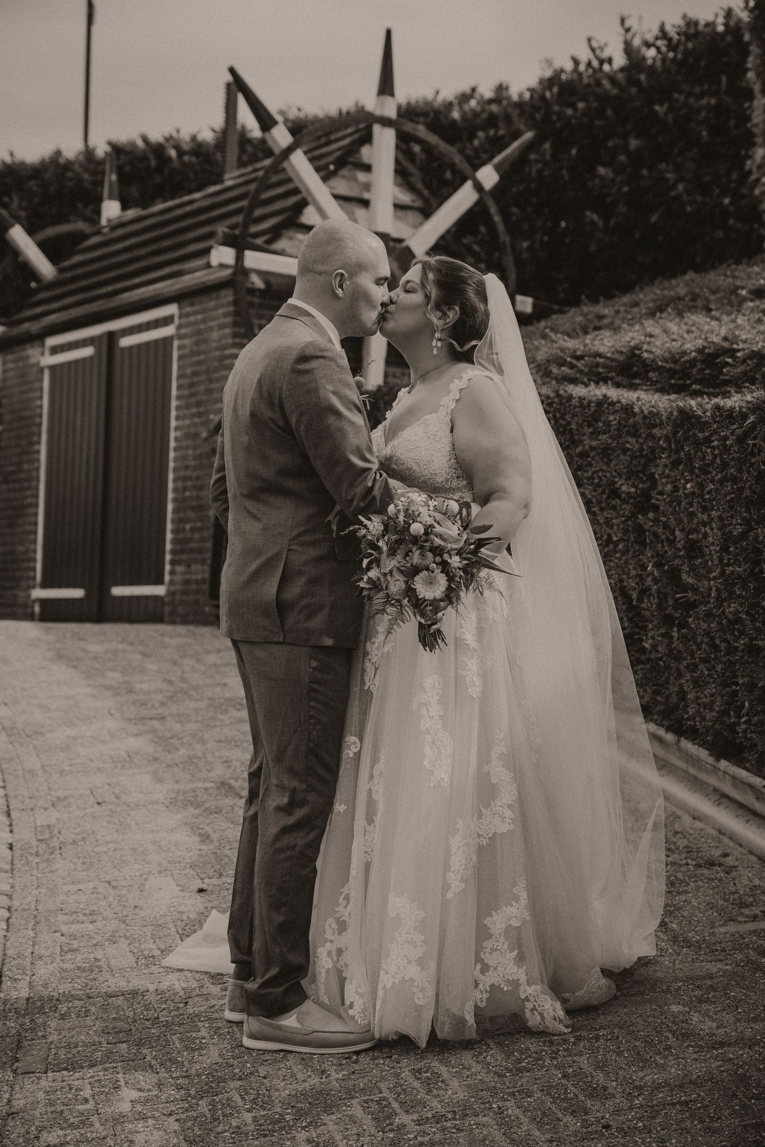 A romantic wedding couple shares intimate moments in a garden setting, captured in a series of black and white photos.