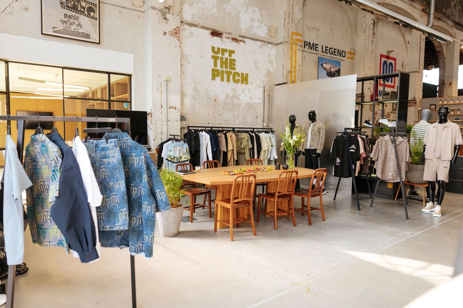 Vintage clothing store interior with denim jackets, wooden furniture and clothing racks in an industrial space.
