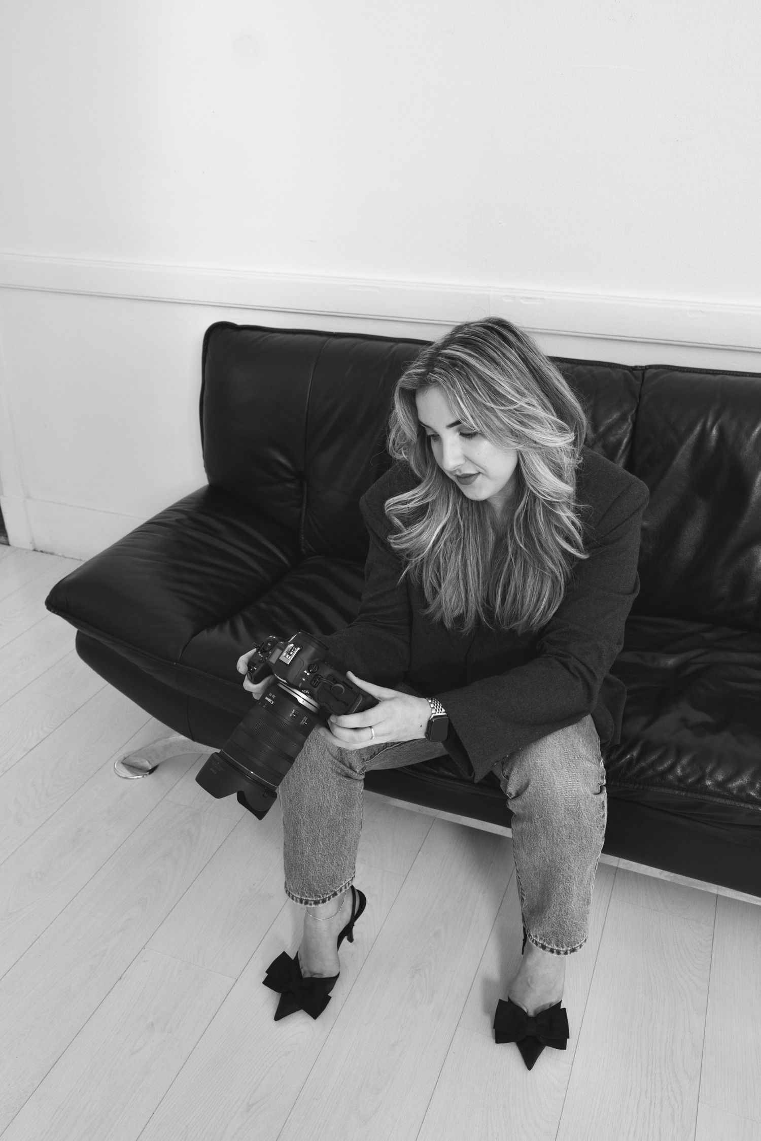 A dynamic sequence of someone falling backwards onto a black leather couch in a minimalist white room.