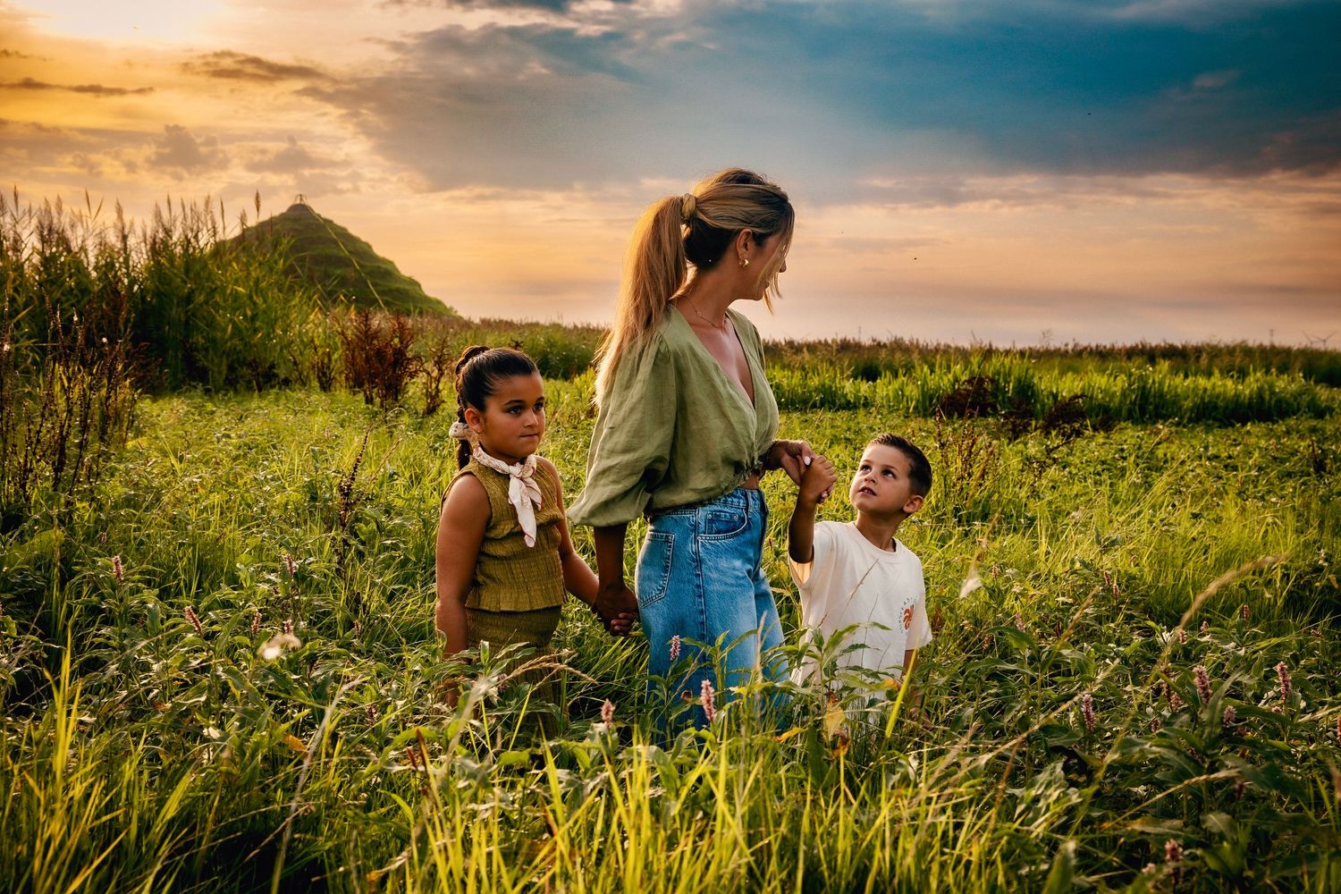 Family enjoying a golden sunset in a scenic meadow during summer.