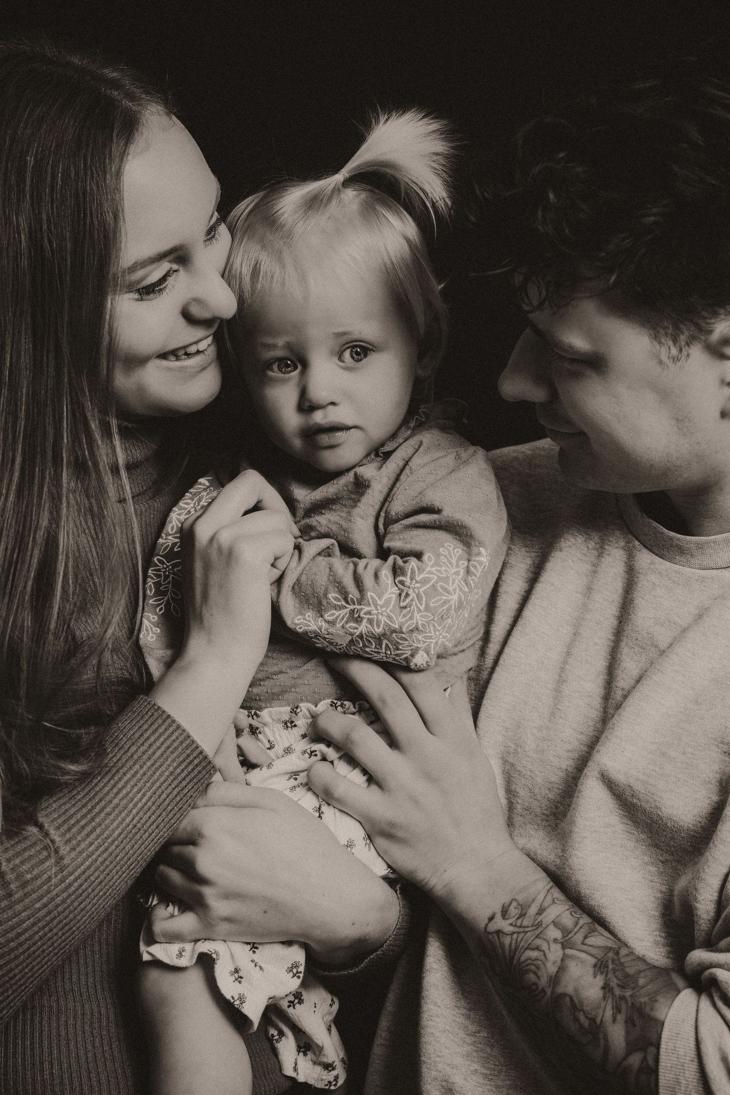 A series of intimate black and white photographs showing tender family moments between parents and child.