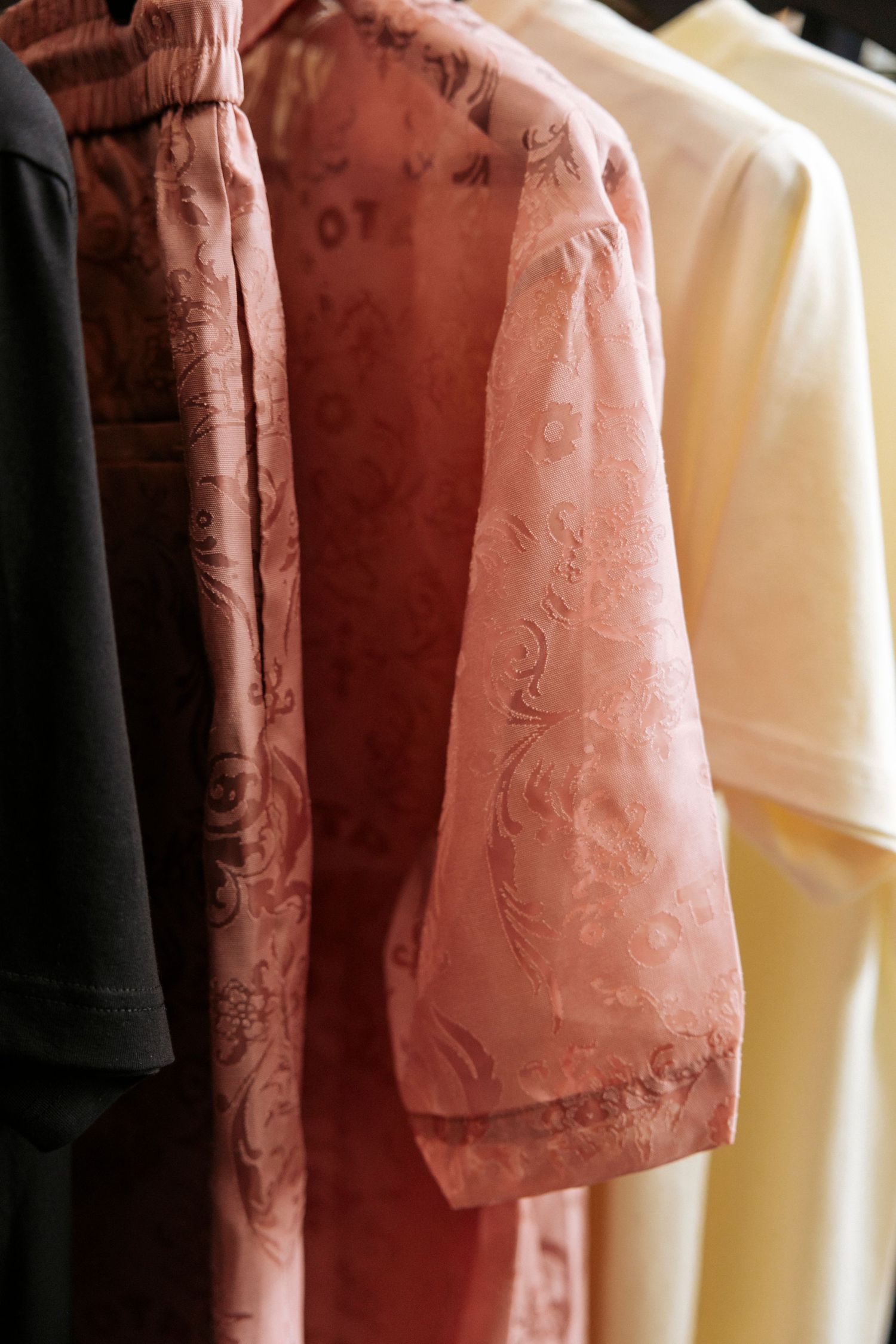 Close-up view of clothing hanging on a rack showing pink and white garments with delicate floral patterns.