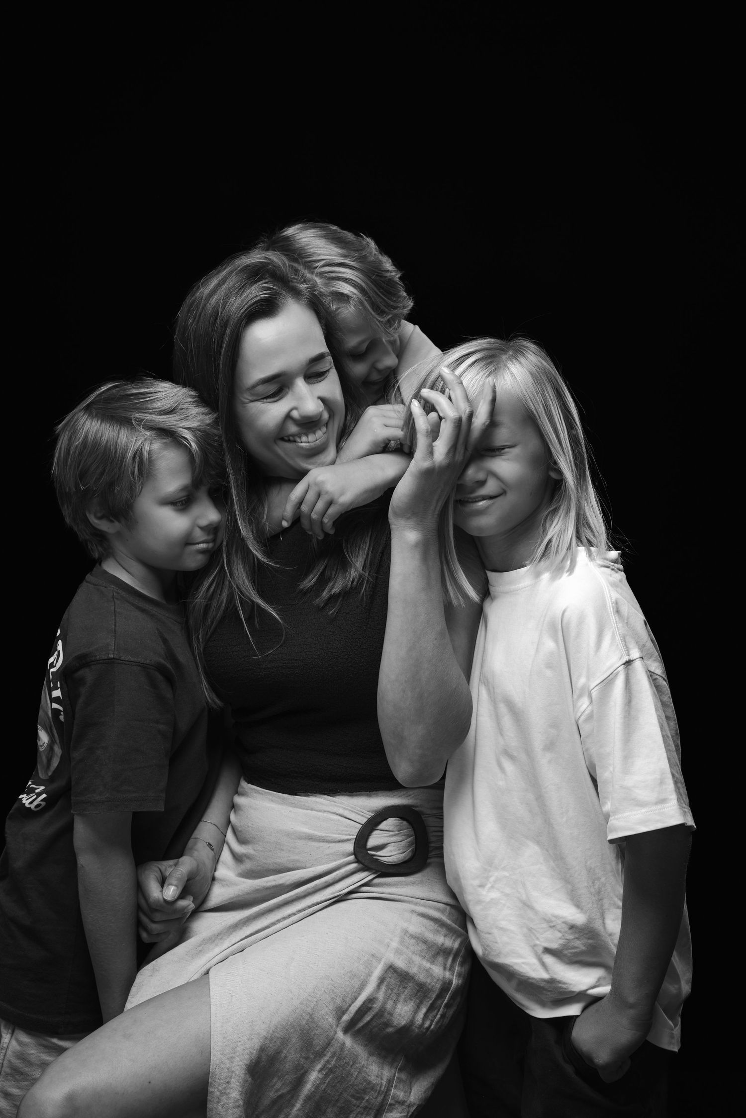 A black and white candid photograph captures a joyful moment of shared laughter and closeness between three people.