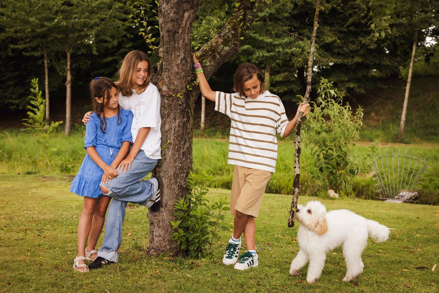 A group enjoying a sunny day outdoors with a large white dog in a grassy park setting.