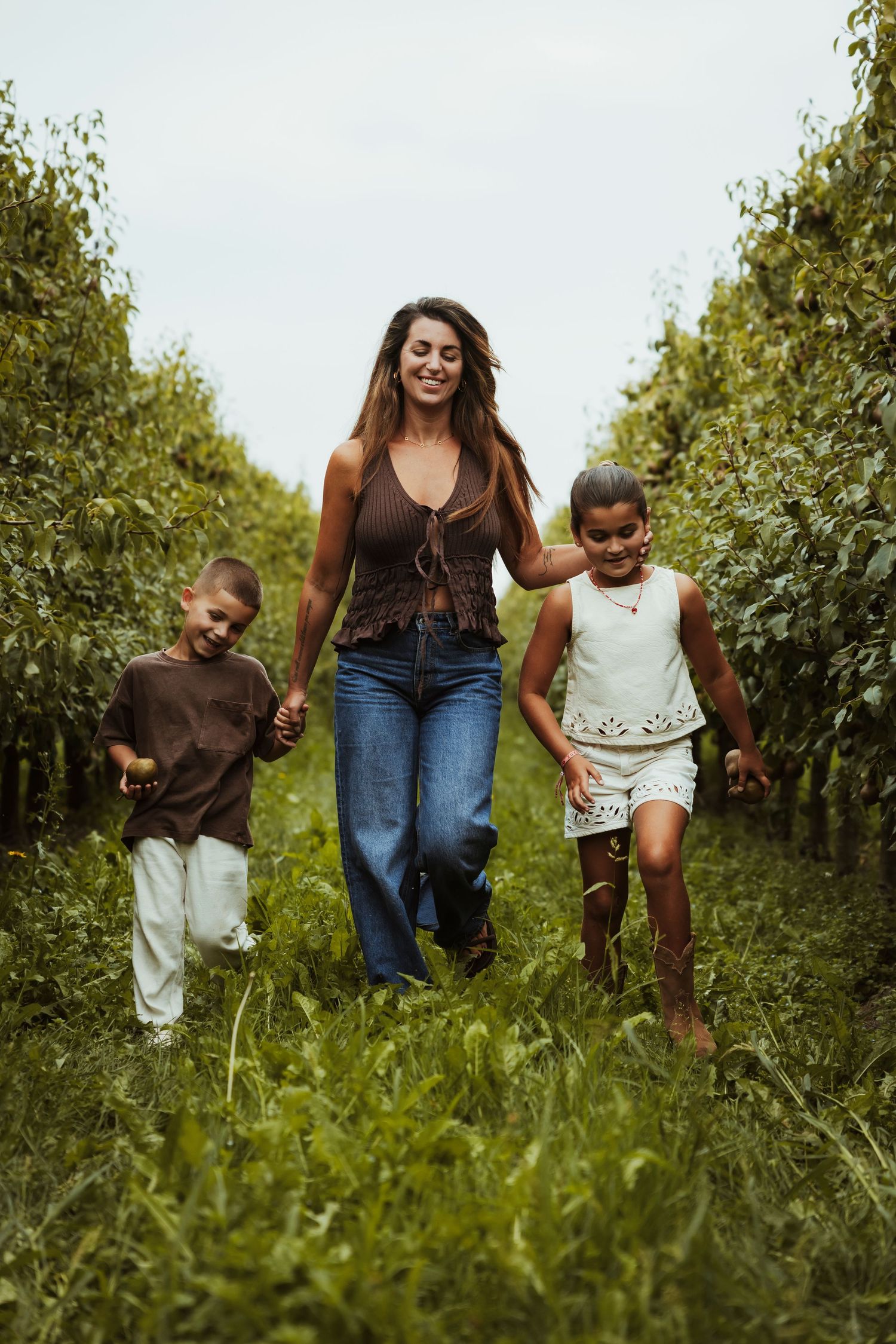 A sequence of four photos showing a playful moment in a grassy field with children and an adult jumping together.