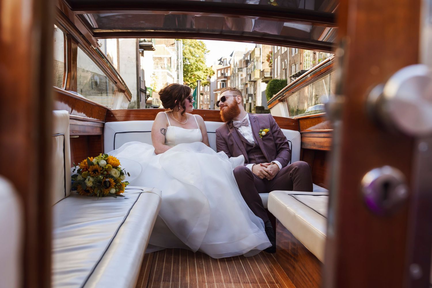 Wedding couple shares an intimate moment while sitting in a wooden water taxi in Venice, Italy.