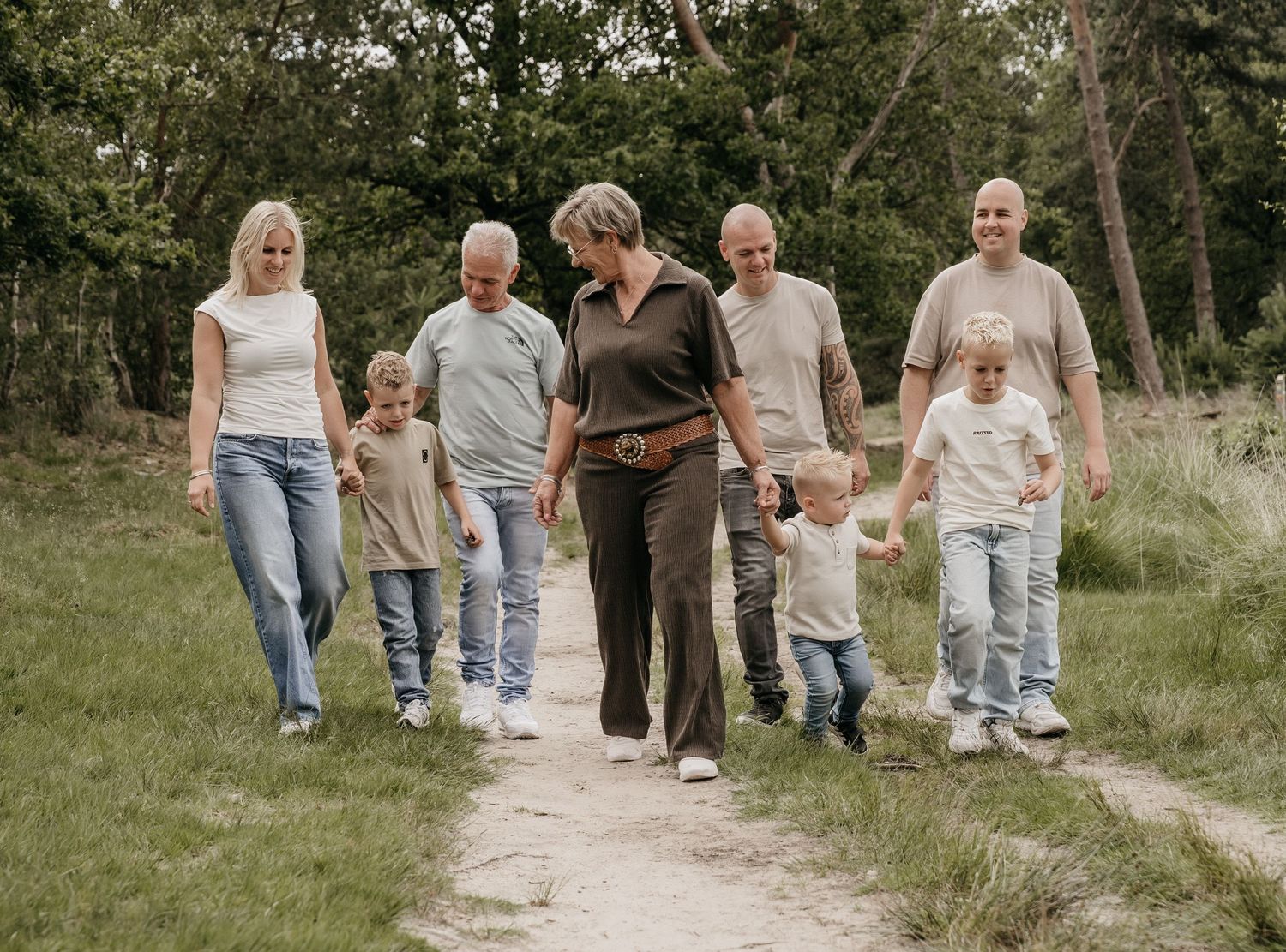 Multi-generational family walking together on a scenic nature path surrounded by lush green trees.