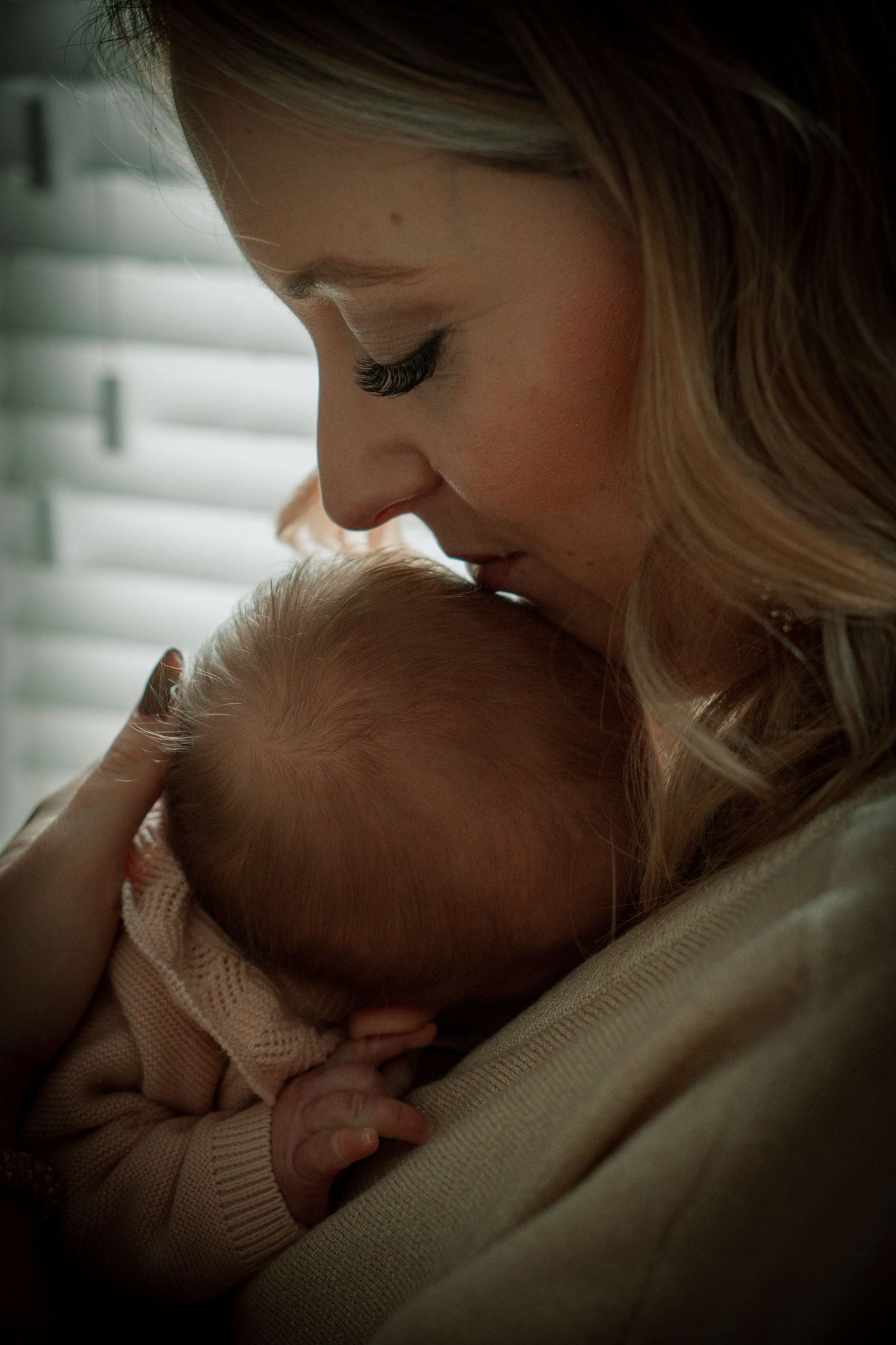 Intimate series of tender moments between parent and newborn baby in soft, moody lighting.