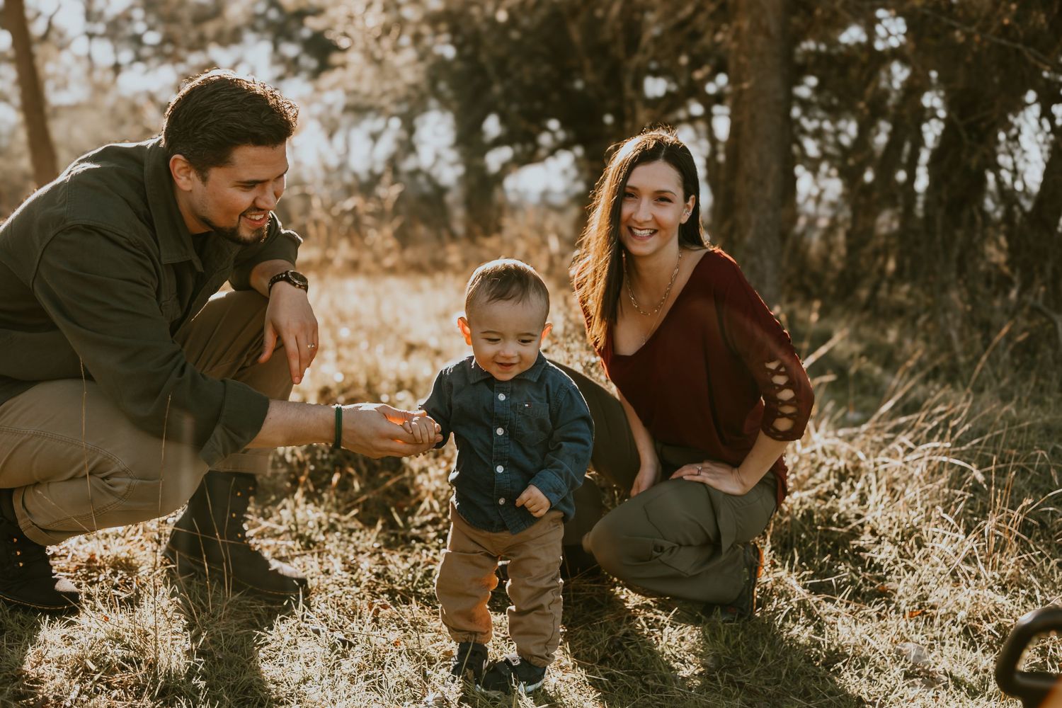 Family spending time together outdoors on an autumn day with sunlight filtering through trees in the background.