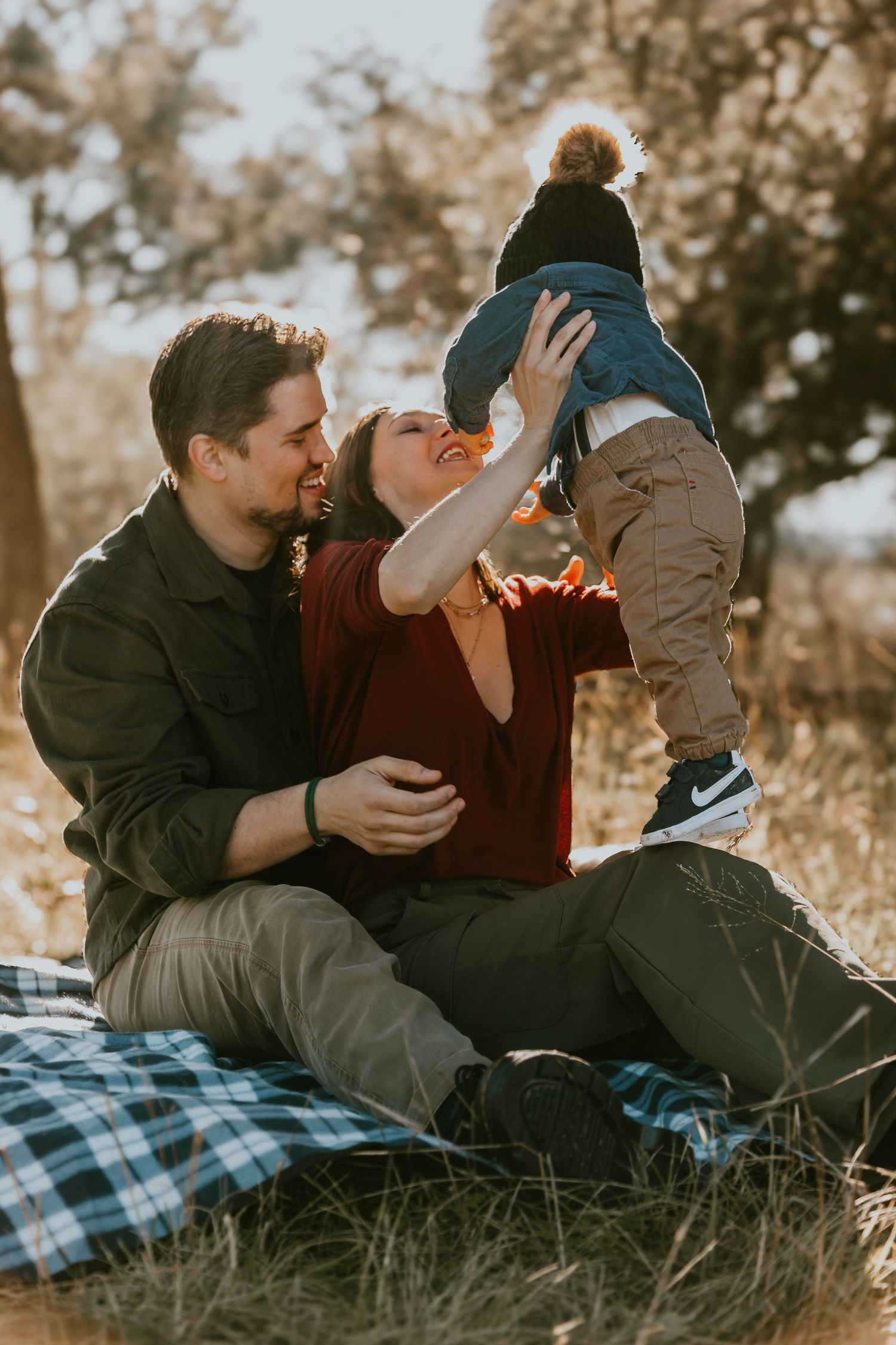 Cherished family moment captured on picnic blanket in autumn field during golden hour sunset.