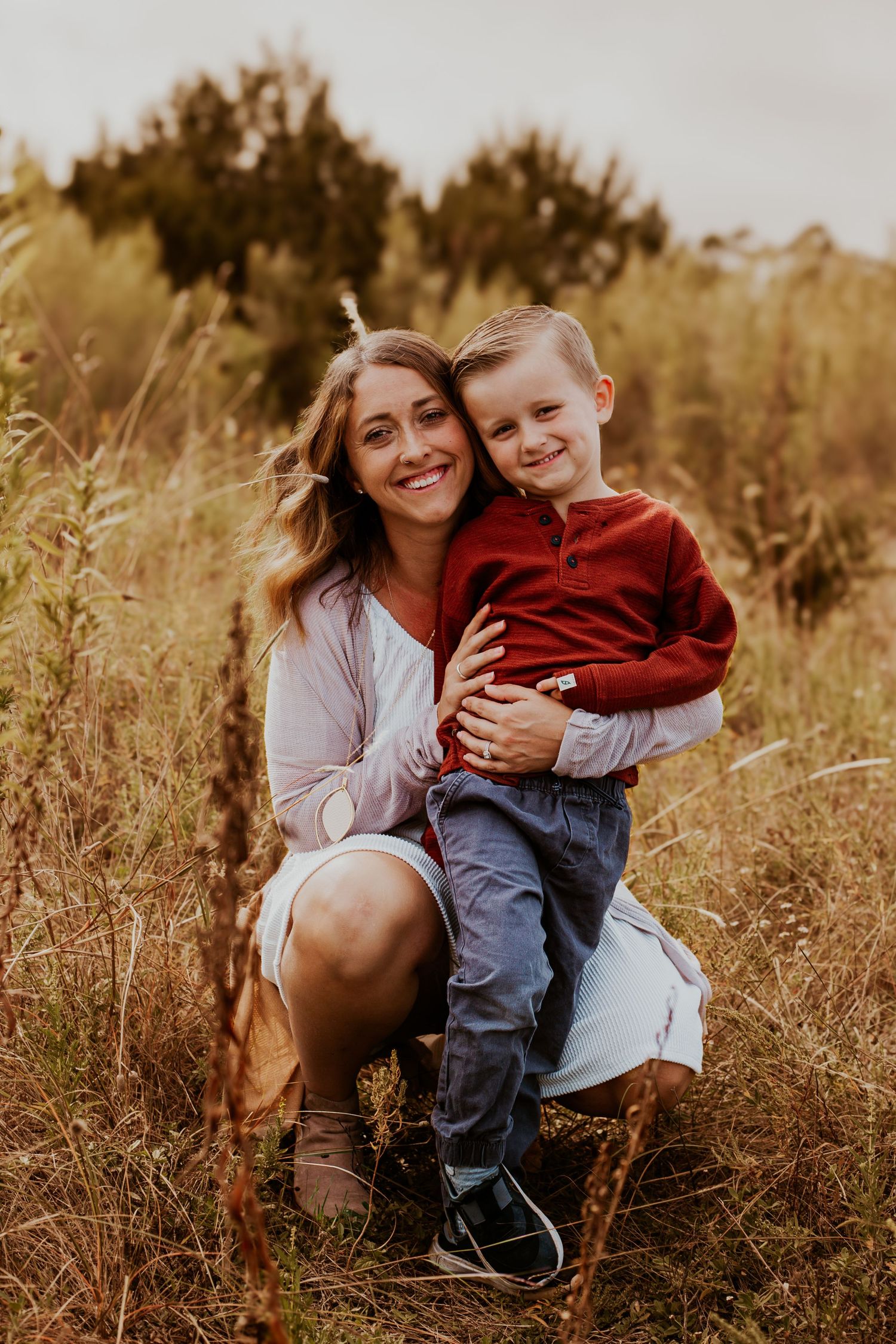 A tender outdoor portrait showing caring family members embracing in a golden field at sunset.