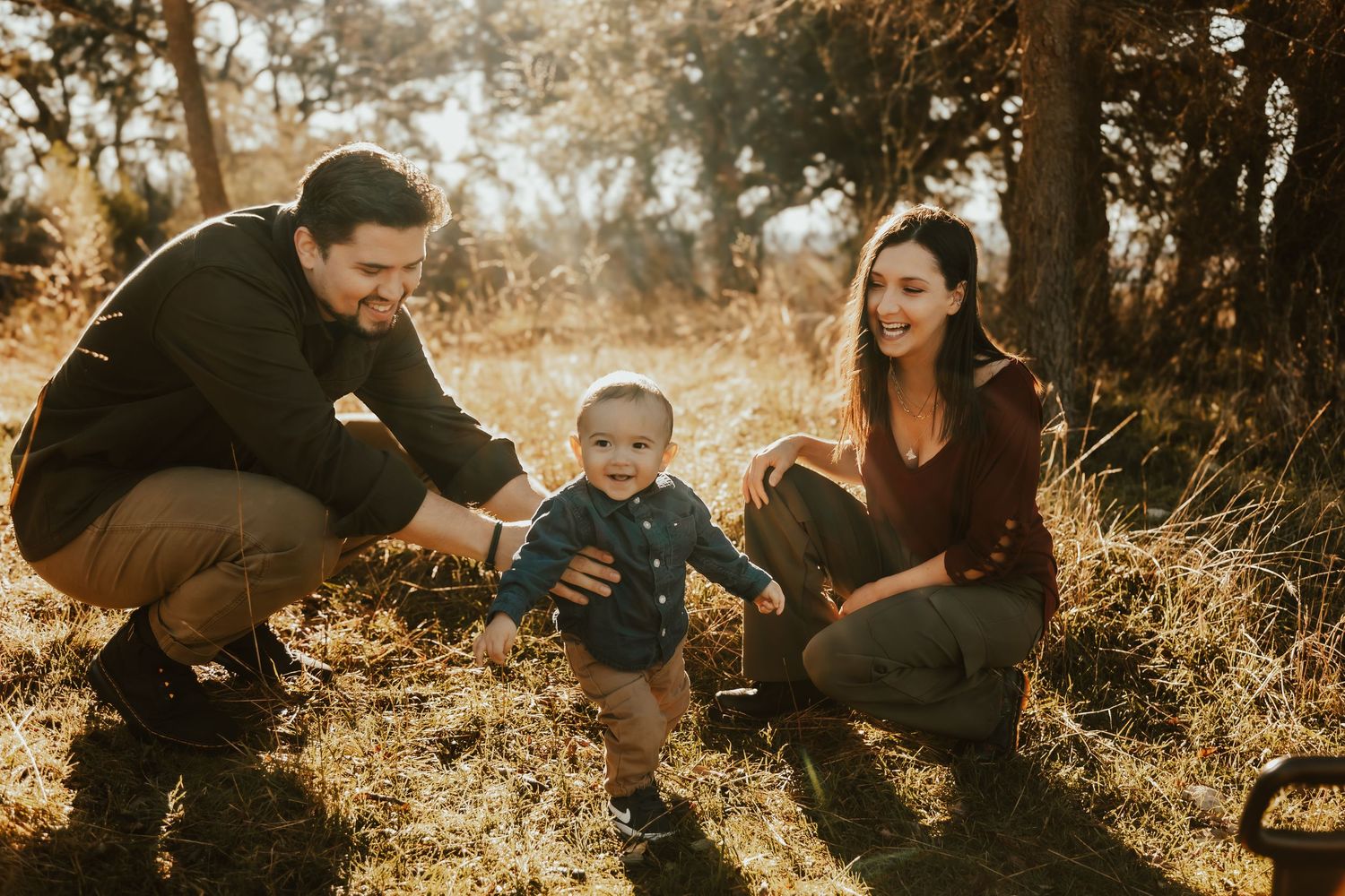 Family enjoying a tender moment together in autumn field at sunset.
