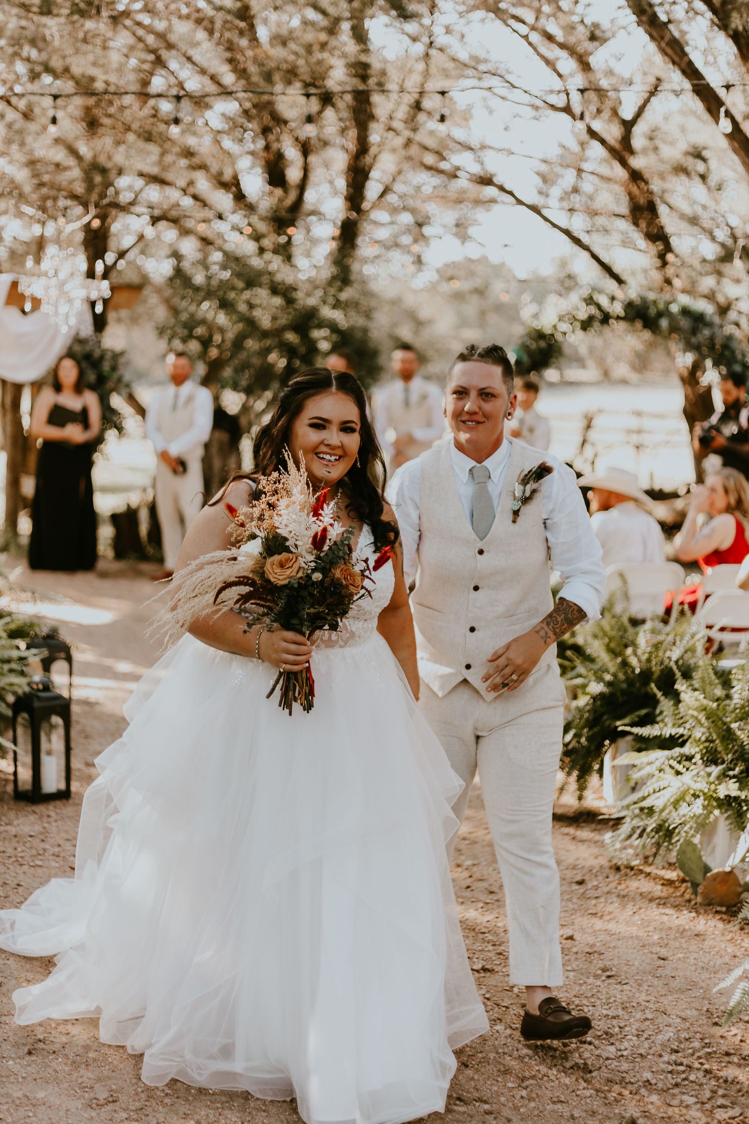A happy couple walks down an outdoor aisle during their garden wedding ceremony.