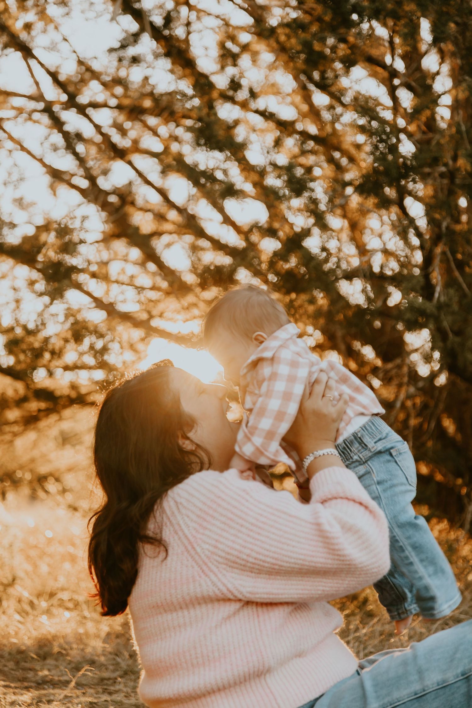 A tender moment captured at sunset with a parent and child playing together in warm golden light among autumn trees.