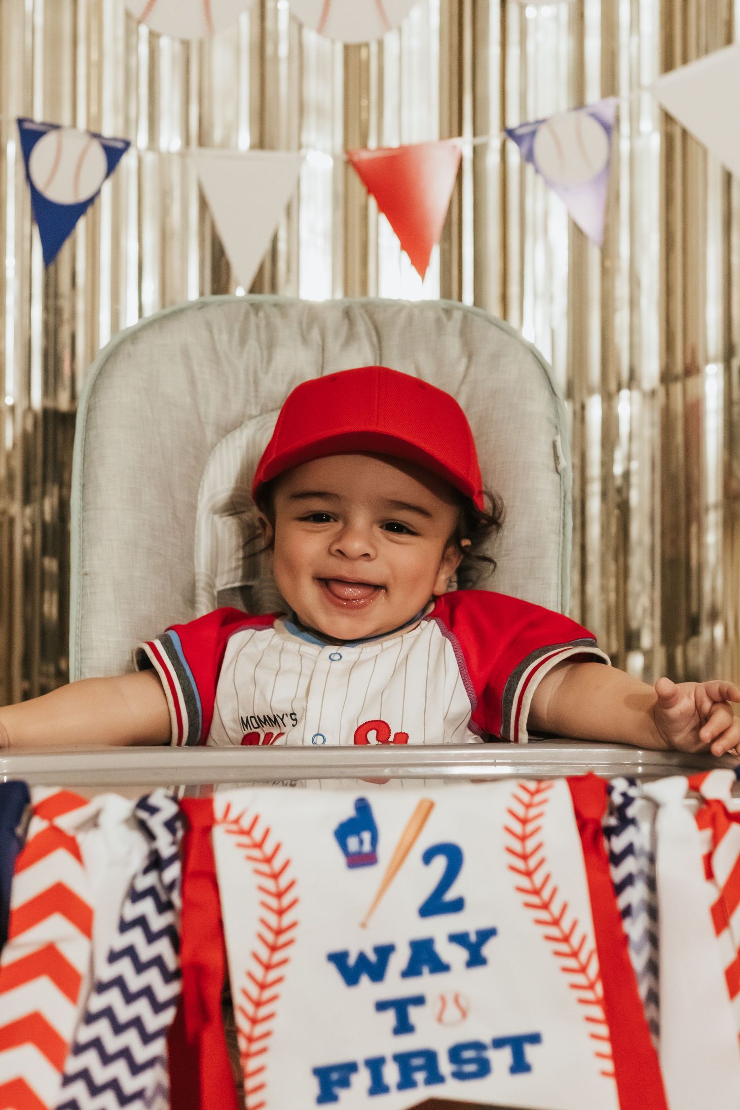 Baseball themed party decorations featuring red and navy bunting with 'Way First' text and a highchair in center.