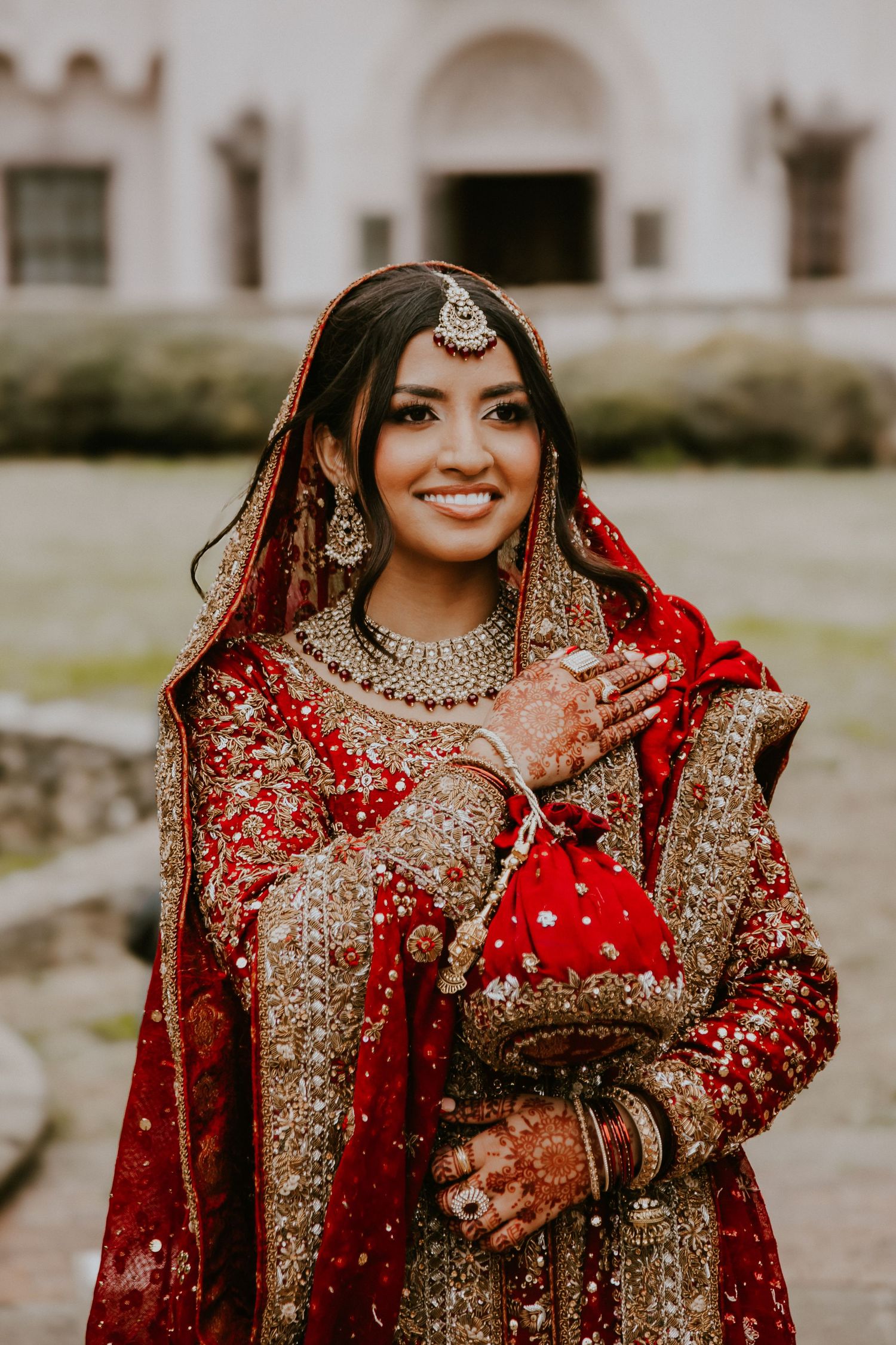 Traditional South Asian bride wearing ornate red and golden lehenga with detailed embroidery and cultural jewelry.