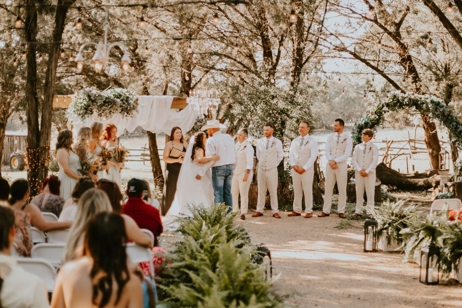 Outdoor wedding ceremony setup in rustic garden setting with white chairs, foliage decorations and golden autumn light in Lampasas Texas.