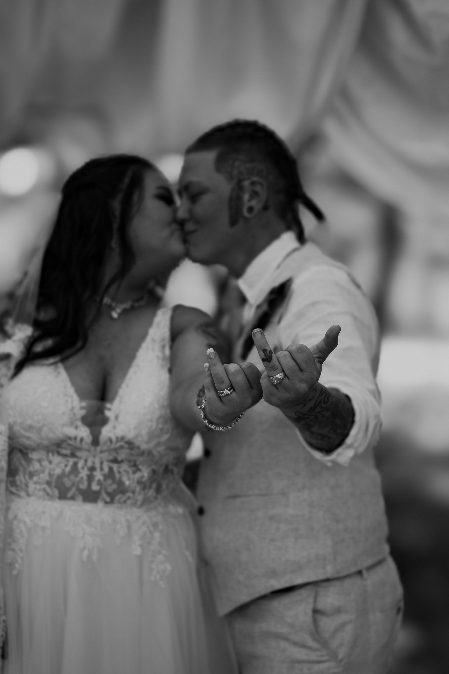 A romantic black and white wedding photo shows newlyweds sharing a kiss while showing off their rings.