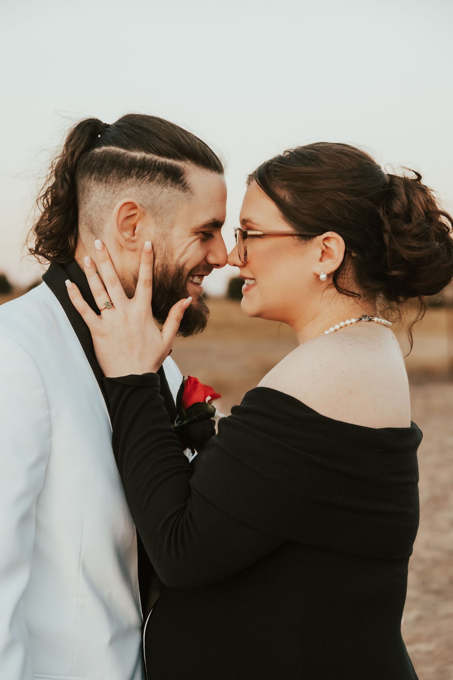 Joyful couple laughing together during romantic sunset photoshoot, wearing contrasting black and white formal attire.