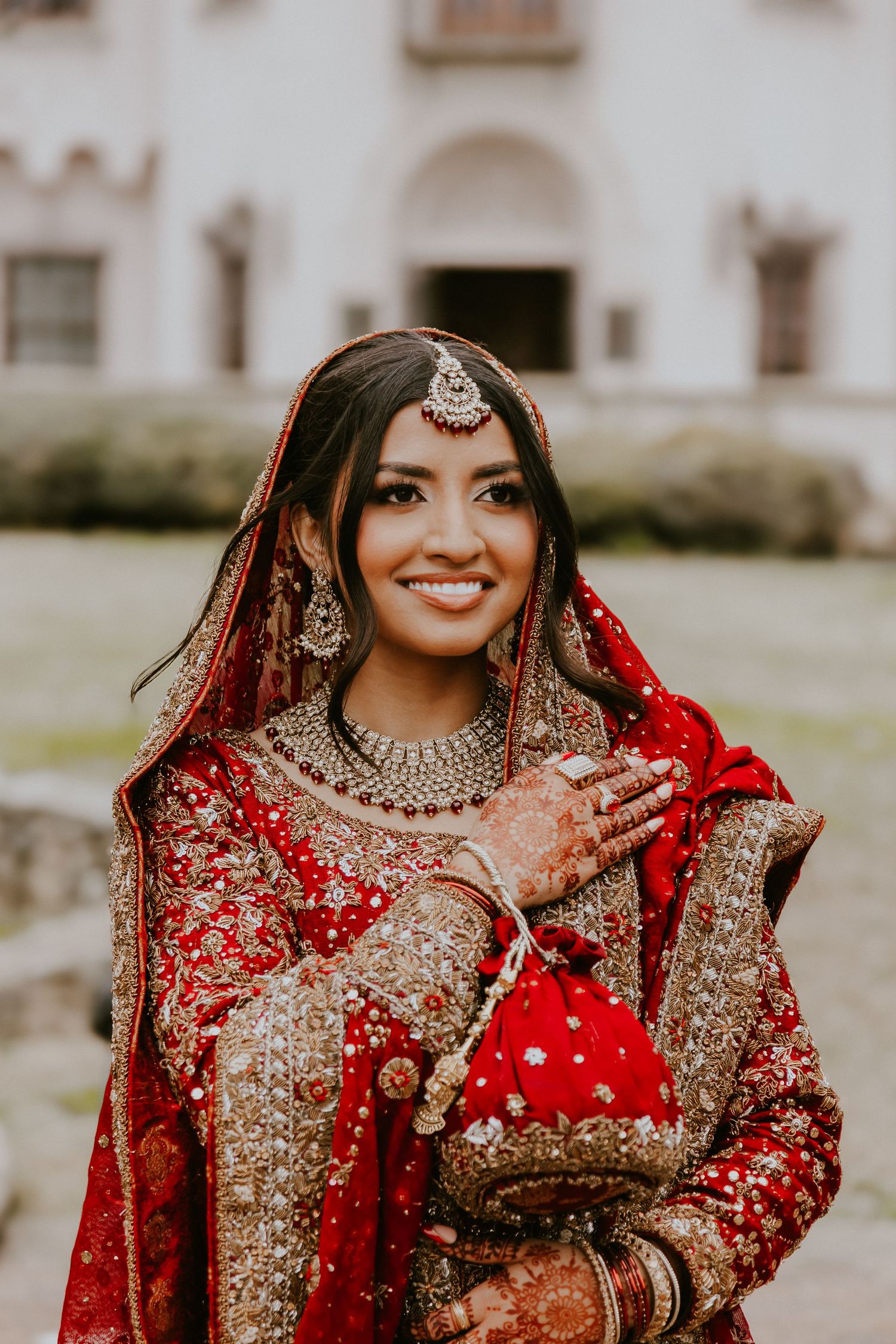 Traditional South Asian bridal attire featuring an ornate red lehenga with gold embellishments and jewelry.