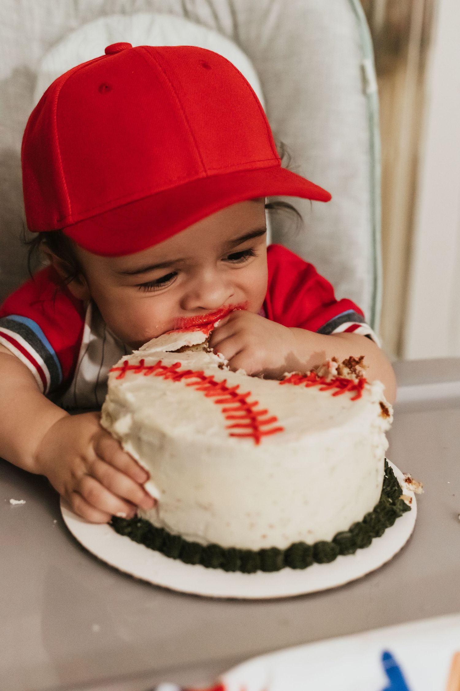 A baseball-themed birthday cake with white frosting and red stitching design is about to be enjoyed.