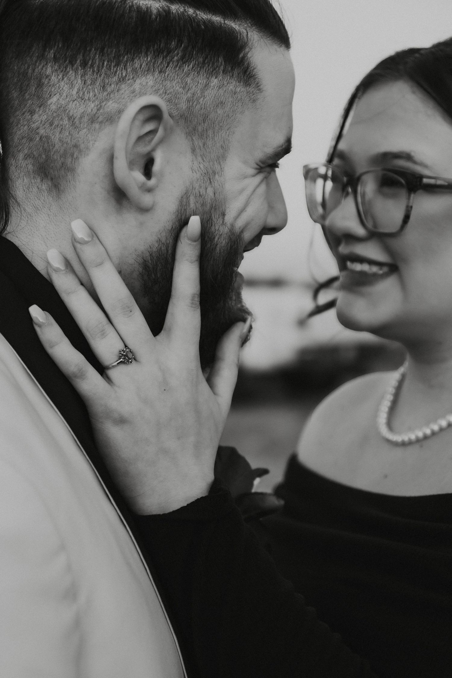 Black and white intimate close-up photo of a couple sharing a tender romantic moment together as one touches the other's face.