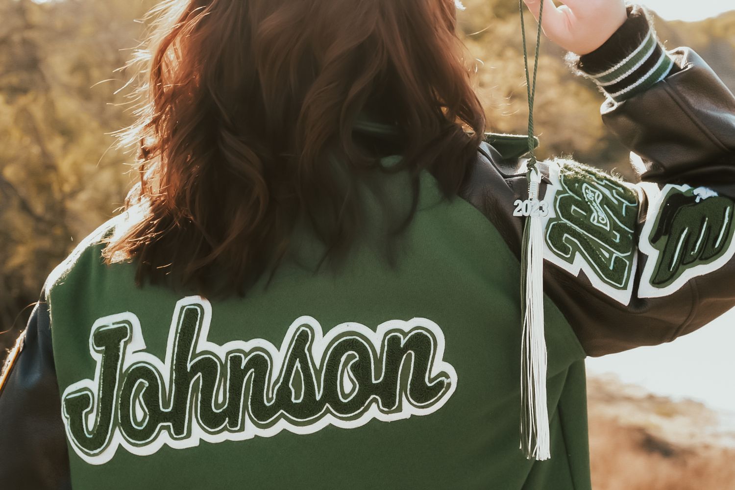 Close-up view of a green varsity jacket with 'Johnson' embroidered text in white lettering.