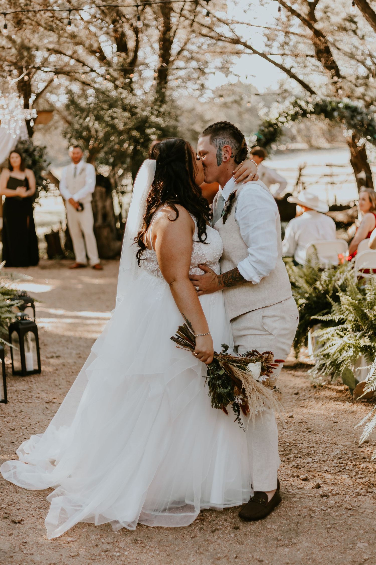 A bride and groom share an intimate dance moment outdoors under trees at a romantic daytime wedding ceremony.