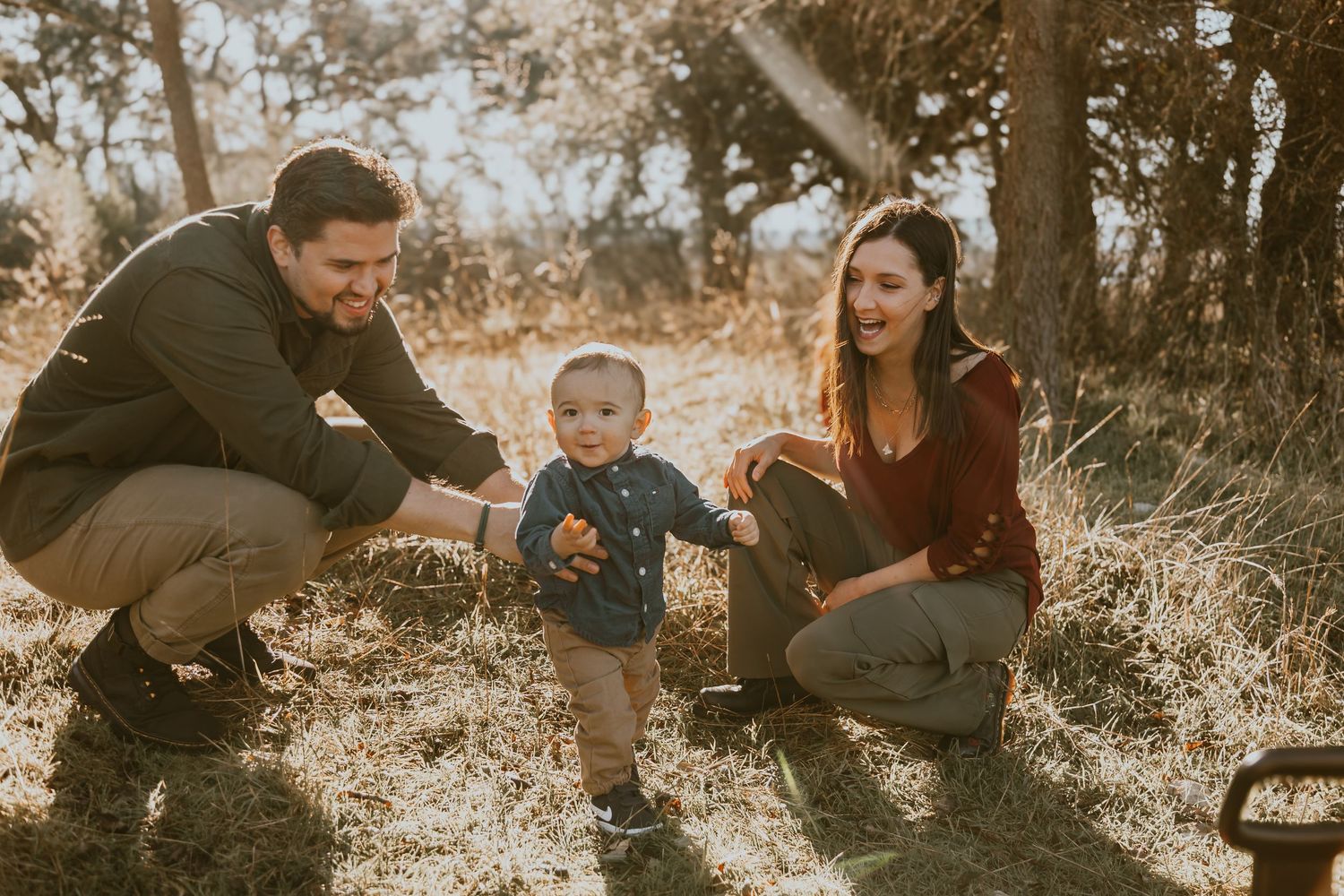 Family enjoying a warm autumn day together in a golden-lit wooded outdoor setting.